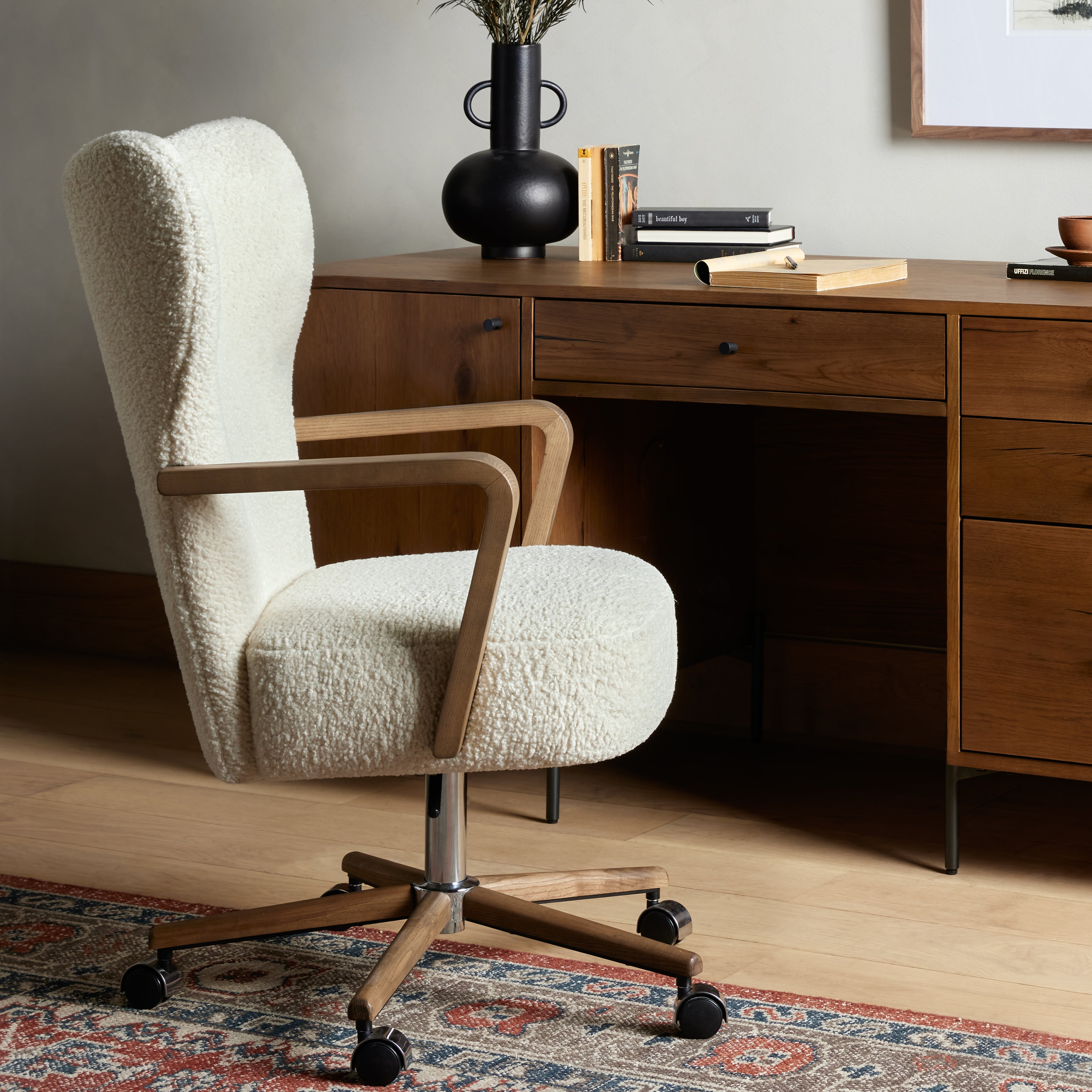 A comfort-driven desk chair features soft, textural upholstery, framed by solid ash arms. A height-adjustable swivel base with casters makes for ease in the modern office. Amethyst Home provides interior design, new home construction design consulting, vintage area rugs, and lighting in the Oklahoma City metro area.