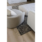 Modern beige sofa with textured cushions on a dark patterned rug in a living room.