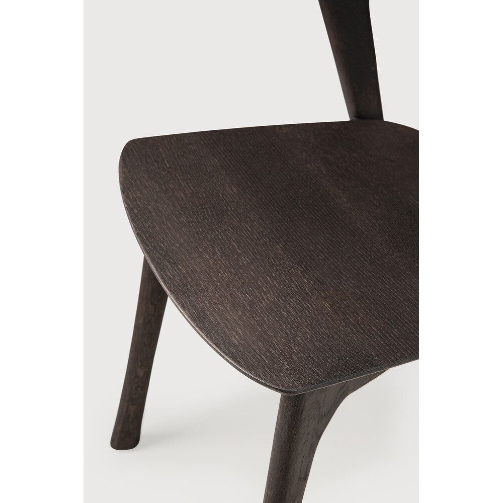 Over the years, the Bok dining chair has become one of our most recognisable designs. Designer Alain van Havre combines sculptural elegance and contemporary crafting into a graceful and airy form.

Seating height: 46cm - 18".
Made from brown tainted oak with a varnish finish. Amethyst Home provides interior design, new construction, custom furniture, and area rugs in the Omaha metro area