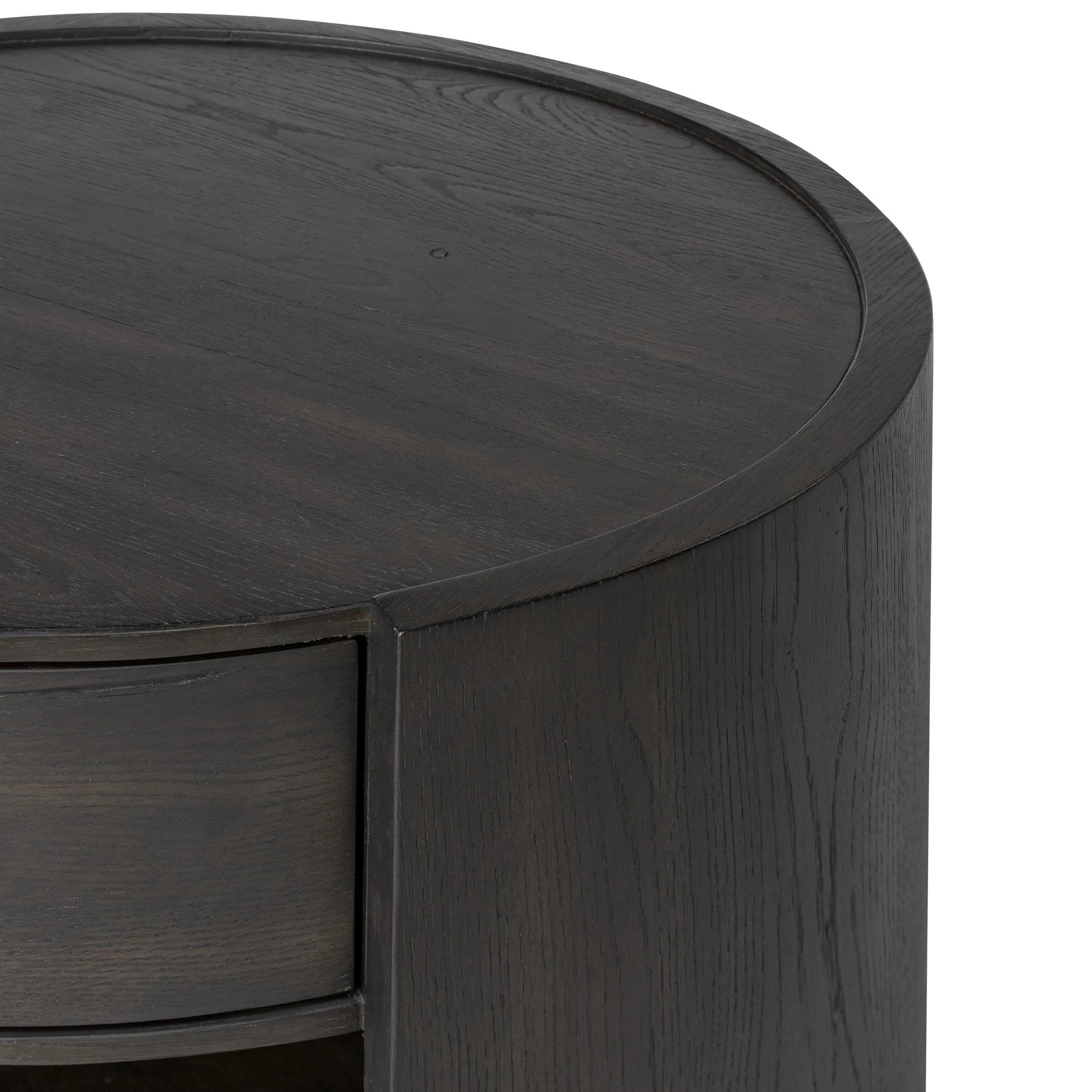Rich contours bring character to the bedside. A round black-finished oak table has a spacious cubby and a single drawer with metal glides and a bronzed pull Amethyst Home provides interior design, new home construction design consulting, vintage area rugs, and lighting in the Miami metro area.