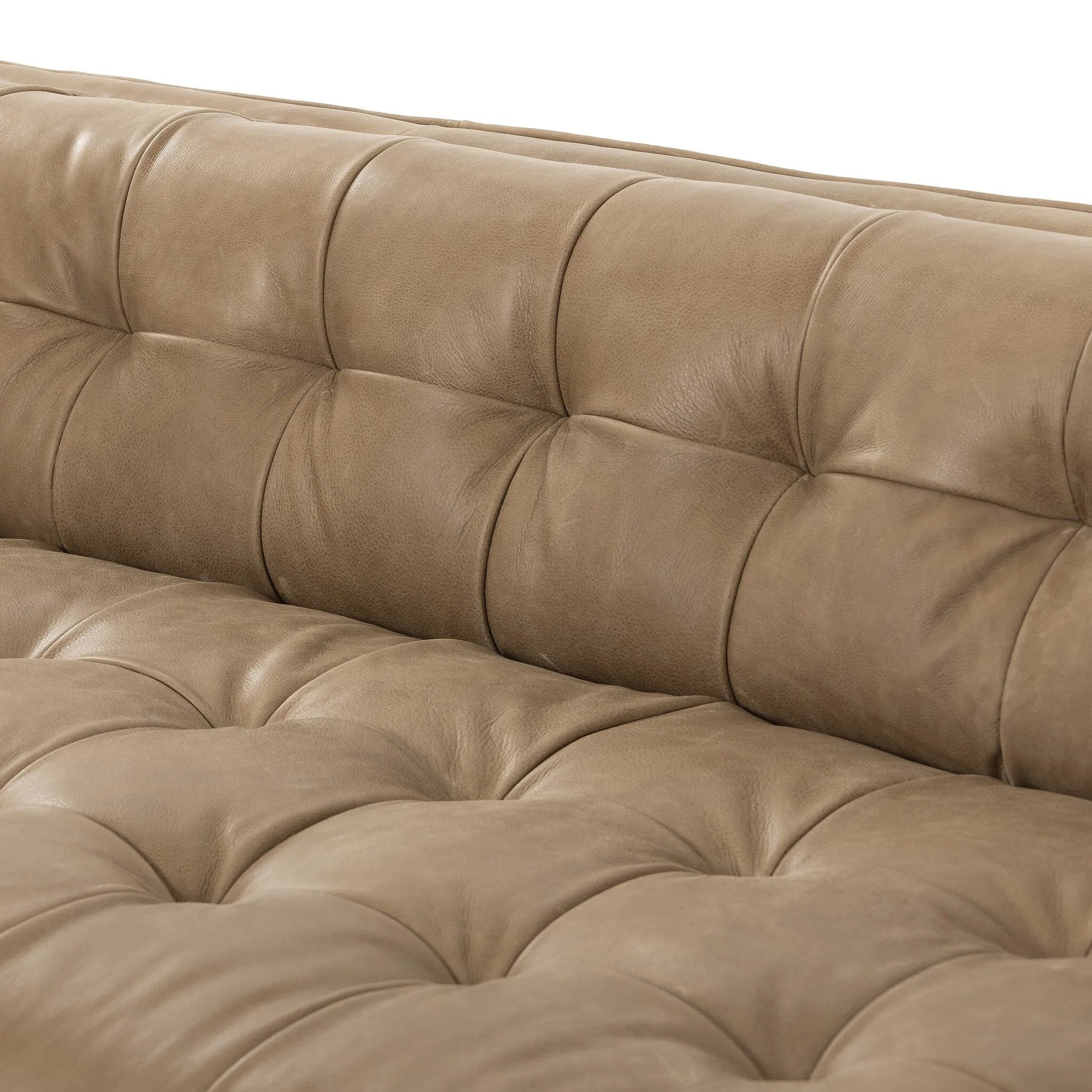 A modernized midcentury silhouette meets the traditional Chesterfield sofa, all in a compact profile perfect for smaller spaces. Top-grain leather in a tan hue, button tufting and a smooth touch bring deep comfort to lounging Amethyst Home provides interior design, new home construction design consulting, vintage area rugs, and lighting in the Charlotte metro area.