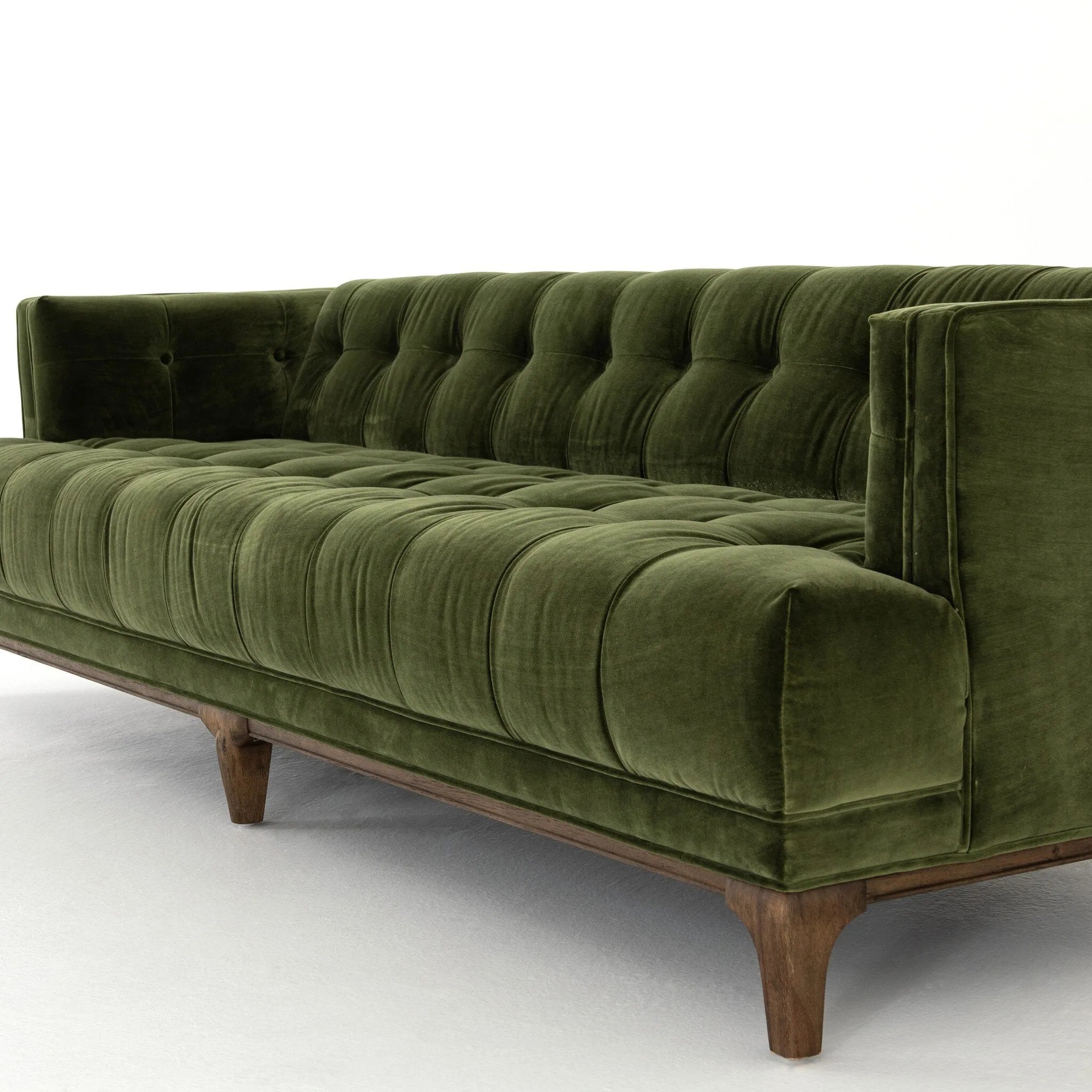 A modernized midcentury silhouette meets the traditional Chesterfield sofa, all in a compact profile perfect for smaller spaces. Smooth velvet in an olive hue, button tufting and a soft touch bring deep comfort to lounging Amethyst Home provides interior design, new home construction design consulting, vintage area rugs, and lighting in the Boston metro area.