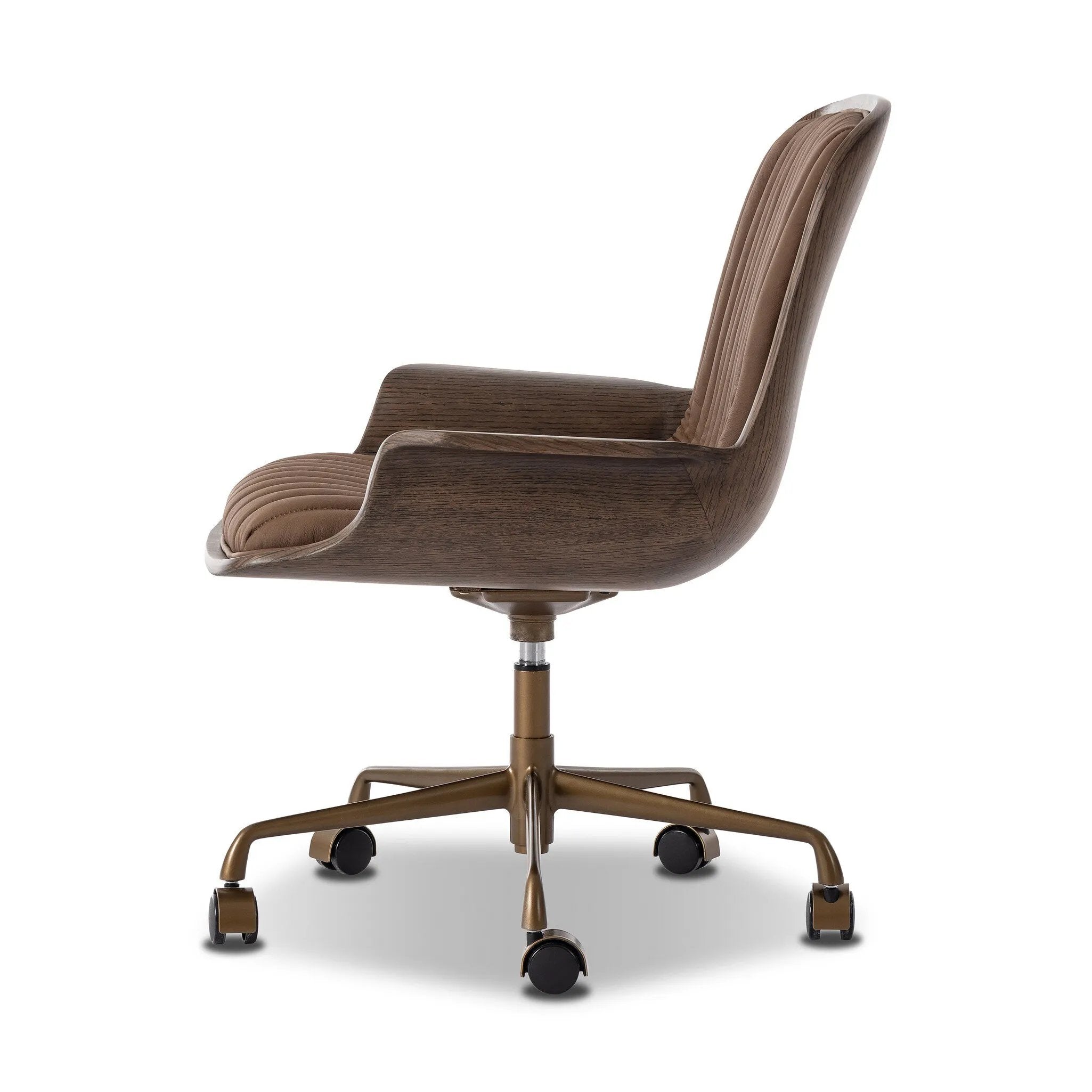 Elevate the office with one easy piece. Inspired by midcentury molded plywood chairs, brown oak veneer frames top-grain leather seat cushioning with slim, soft channeling. A 360-degree swivel burnished brass-finished base with casters allows for easy movement. Amethyst Home provides interior design, new home construction design consulting, vintage area rugs, and lighting in the Kansas City metro area.