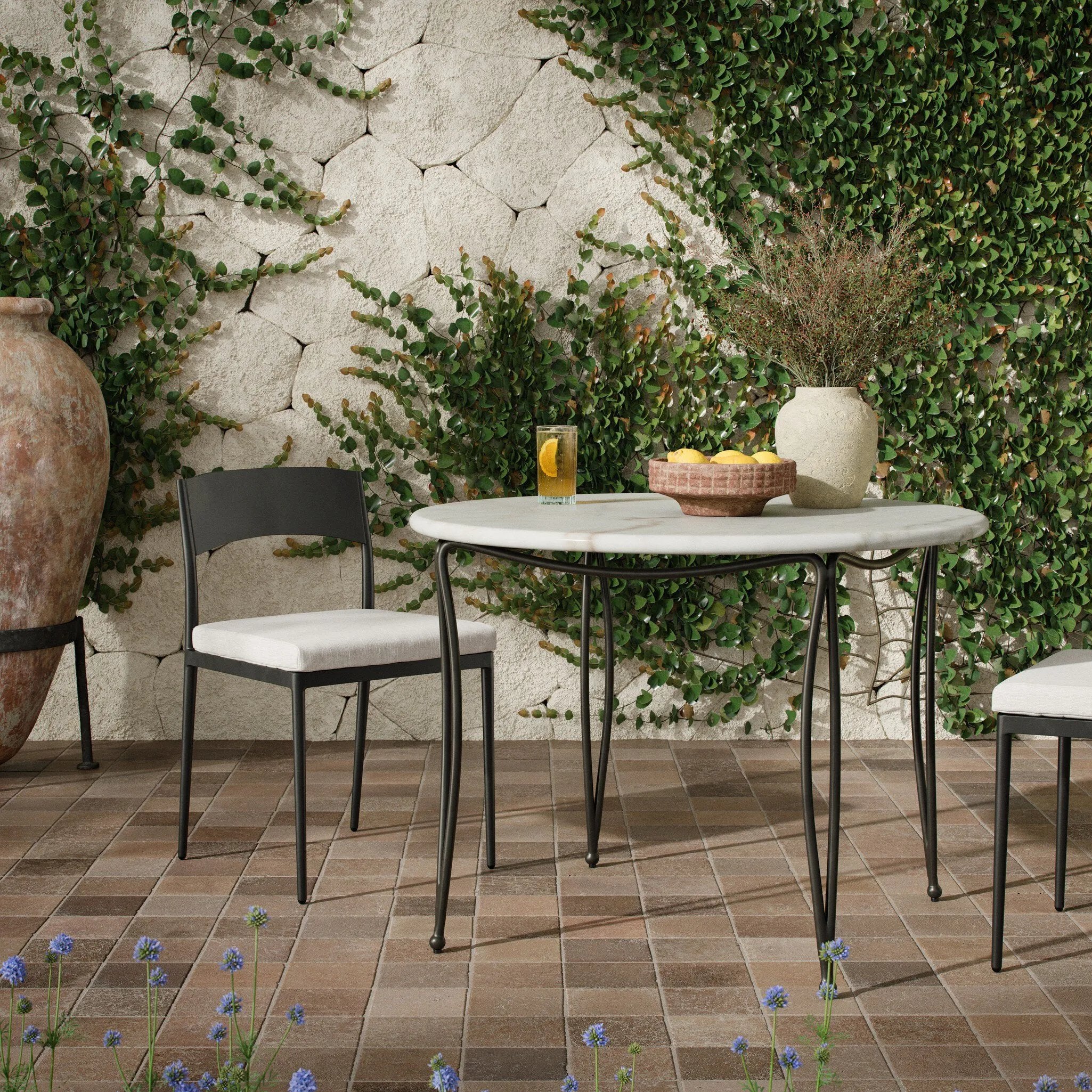 Inspired by Art Deco designs, this outdoor bistro dining table introduces a sense of movement to a classic silhouette. Graceful, flowing lines on the base pair with a white marble top for a classic black-and-white look. Cover or store inside during inclement weather and when not in use. Amethyst Home provides interior design, new home construction design consulting, vintage area rugs, and lighting in the Scottsdale metro area.