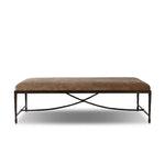 This French Industrialist-inspired cocktail ottoman features a curved stretcher base of bronzed hammered iron and a velvety seat in a versatile earth tone. Style with a sofa or sectional to create an extra surface in your living space, or for bonus seating. Amethyst Home provides interior design, new home construction design consulting, vintage area rugs, and lighting in the Houston metro area.