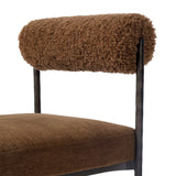 The armless dining chair gets a playful update with a bolstered cylinder seat back. Made from soft shearling and hammered met