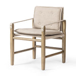 Inspired by a vintage safari-style frame, this dining chair is defined by the fluid strap arms. Semi-attached cushions in taupe performance fabric, finished with button tufting details. Framed out by warm parawood. Amethyst Home provides interior design, new home construction design consulting, vintage area rugs, and lighting in the Austin metro area.