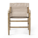 Inspired by a vintage safari-style frame, this dining chair is defined by the fluid strap arms. Semi-attached cushions in taupe performance fabric, finished with button tufting details. Framed out by warm parawood. Amethyst Home provides interior design, new home construction design consulting, vintage area rugs, and lighting in the Seattle metro area.