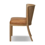 The barrel back dining chair, refreshed. Light oak shapes an armless frame and curved rear legs that almost appear to flow into the seat back. A comfy seat is upholstered in chestnut top-grain leather, while reeding details on the back create a sense of perception play. Amethyst Home provides interior design, new home construction design consulting, vintage area rugs, and lighting in the Boston metro area.