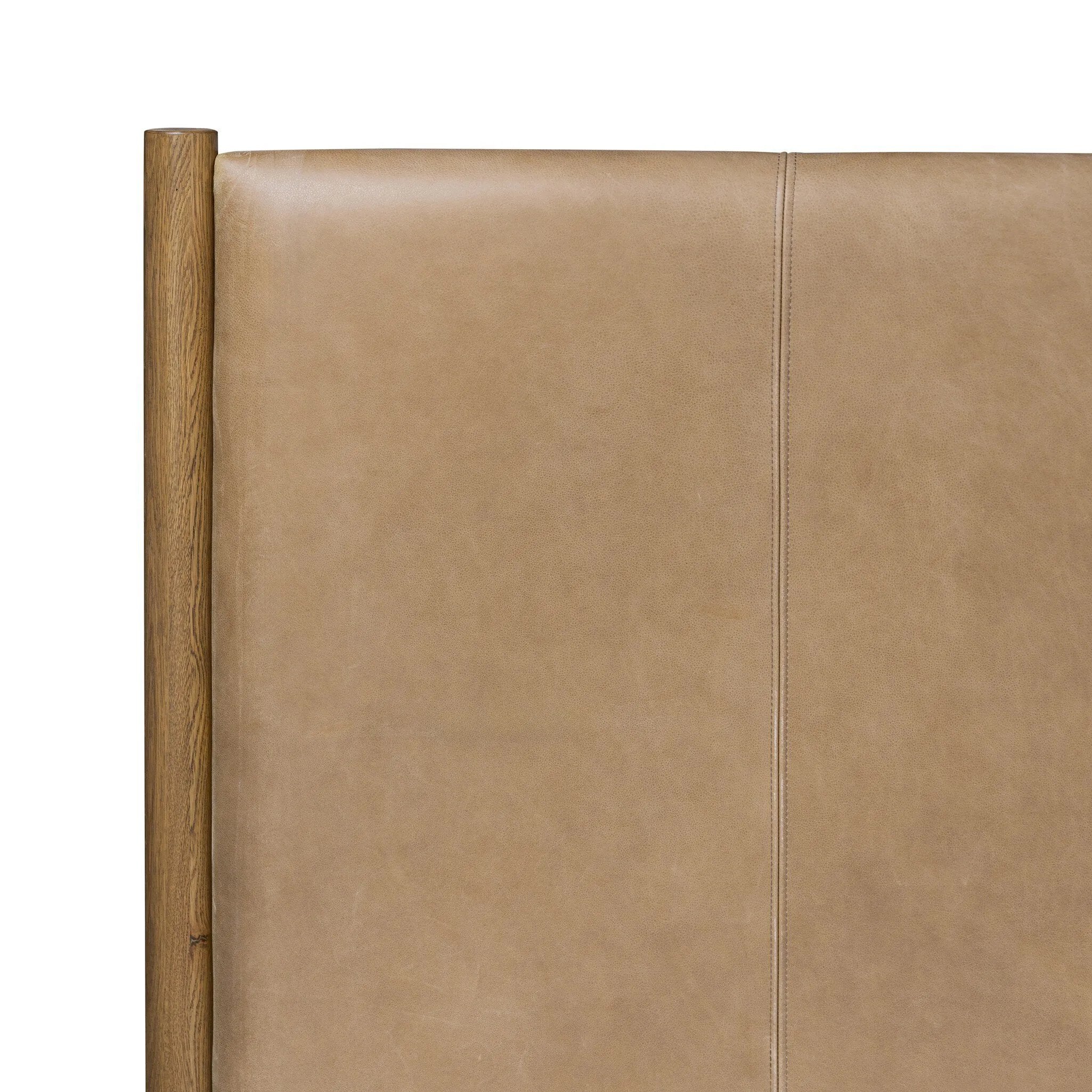 Rounded, chunky dowel legs in an amber oak finish frame the tan top-grain leather headboard of this simple-but-striking bed frame Amethyst Home provides interior design, new home construction design consulting, vintage area rugs, and lighting in the Des Moines metro area.