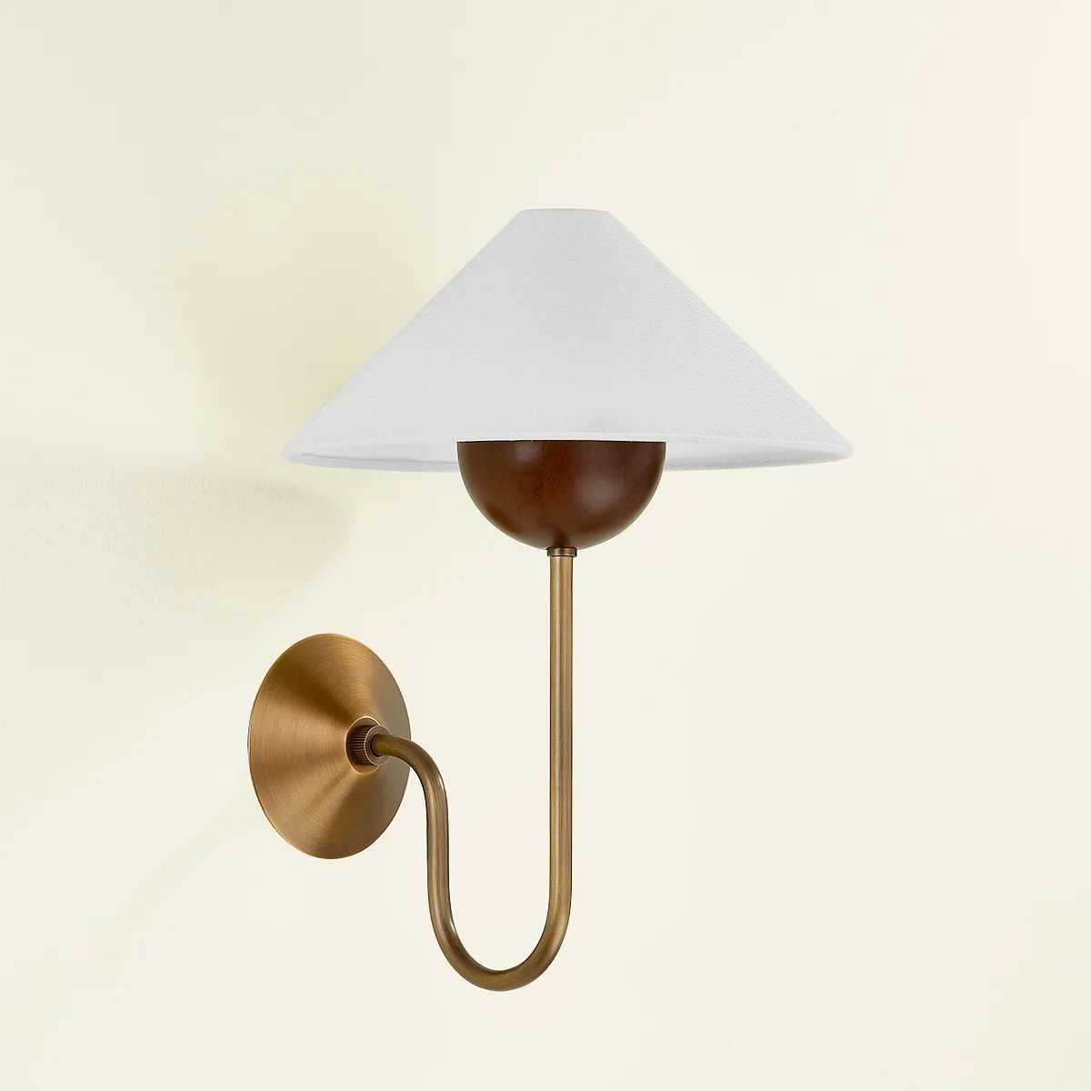Combining geometric shapes and three distinctive earthy materials, the Evan sconce generates its own visual design language. The design-forward composition includes a swooping J-arm in Patina Brass, leading into an overscale walnut wood bobeche. As a note of contrast, the fixture is topped by a sharply tapered shade made from grained white linen.  Amethyst Home provides interior design, new home construction design consulting, vintage area rugs, and lighting in the Houston metro area.