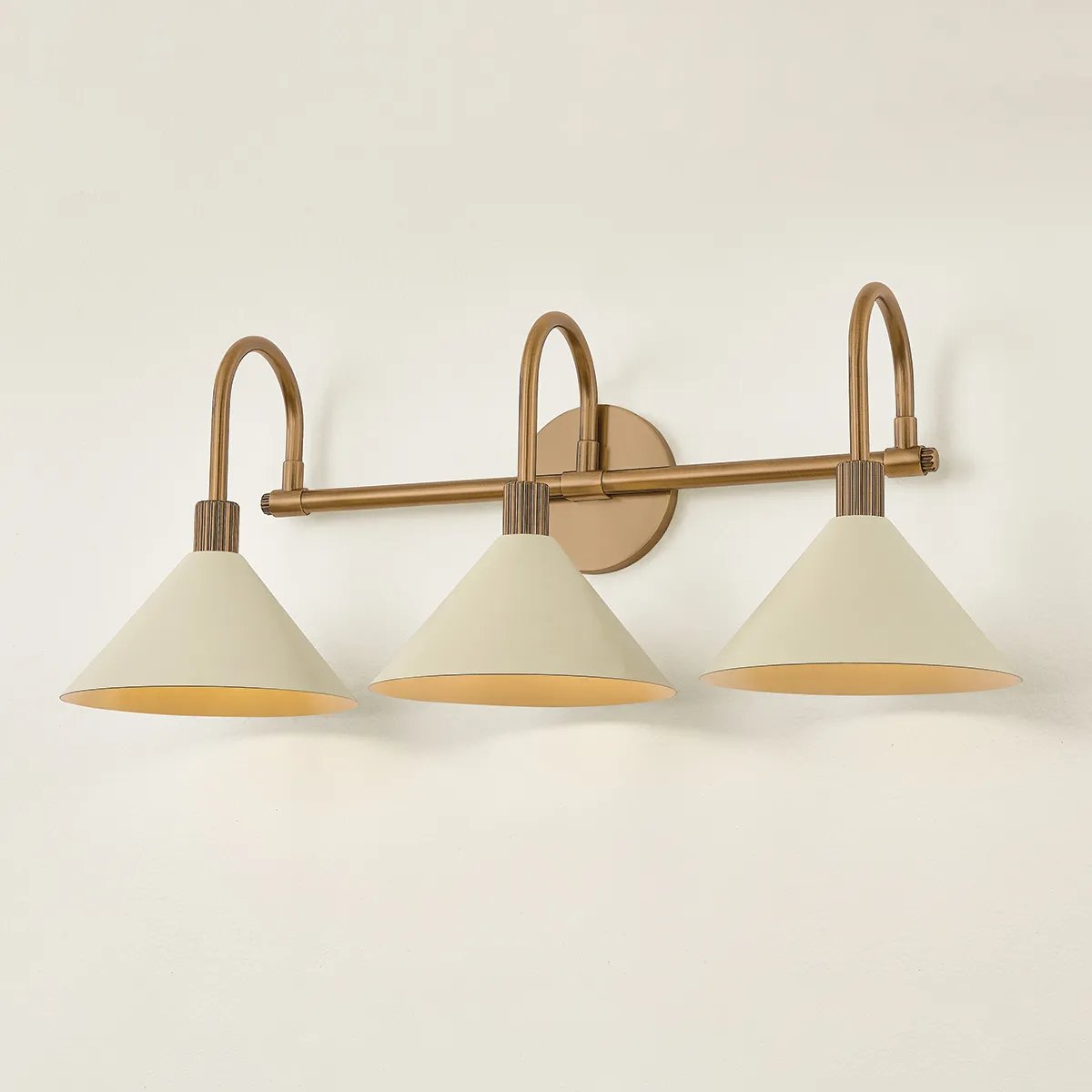 A modern interpretation of Art Deco shapes, the Jovani bath bar features elongated arms and sharply tapered Soft Sand shades. The clean design highlights the connections between elements through pronounced fittings and subtle fluting details. Finished in classic Patina Brass, Jovani is available with 1, 2, or 3 lights. Amethyst Home provides interior design, new home construction design consulting, vintage area rugs, and lighting in the Omaha metro area.