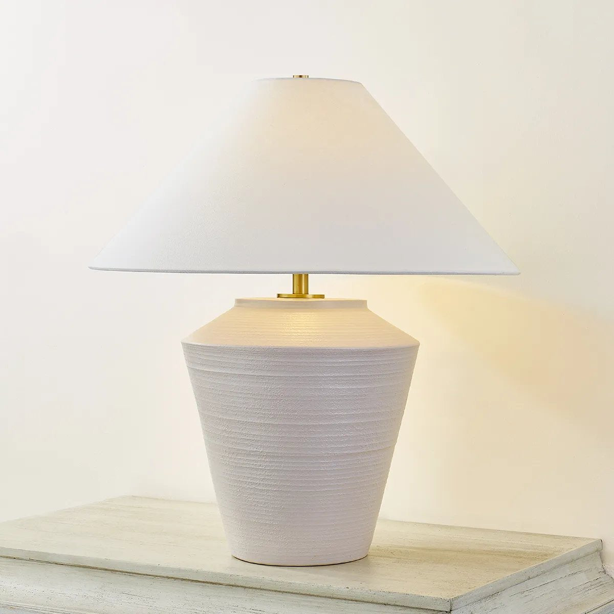 Inspired by raw beauty of the desert, this whitewashed terracotta table lamp is calm and refreshing. The textural body contrasts beautifully with the angular tapered white linen shade. An Aged Brass frame provides a surprising metallic finish. Part of THELIFESTYLEDCO® collection. Amethyst Home provides interior design, new home construction design consulting, vintage area rugs, and lighting in the Winter Garden metro area.