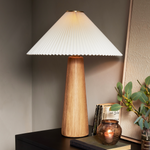 Modern minimal meets traditional. A tapered wood table lamp base is topped with a design-forward pleated shade. Amethyst Home provides interior design, new home construction design consulting, vintage area rugs, and lighting in the Kansas City metro area.
