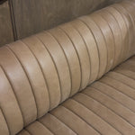 The beauty of this modular piece is that the vertical channeling makes for a cohesive feel despite being modular.  Welcome to your new favorite nook for morning coffee. An L-shaped dining banquette is upholstered in tan top-grain leather with a beautifully pronounced grain and dramatic channeling for a linear look. Perfectly sized for smaller spaces. Amethyst Home provides interior design, new home construction design consulting, vintage area rugs, and lighting in the Dallas metro area.