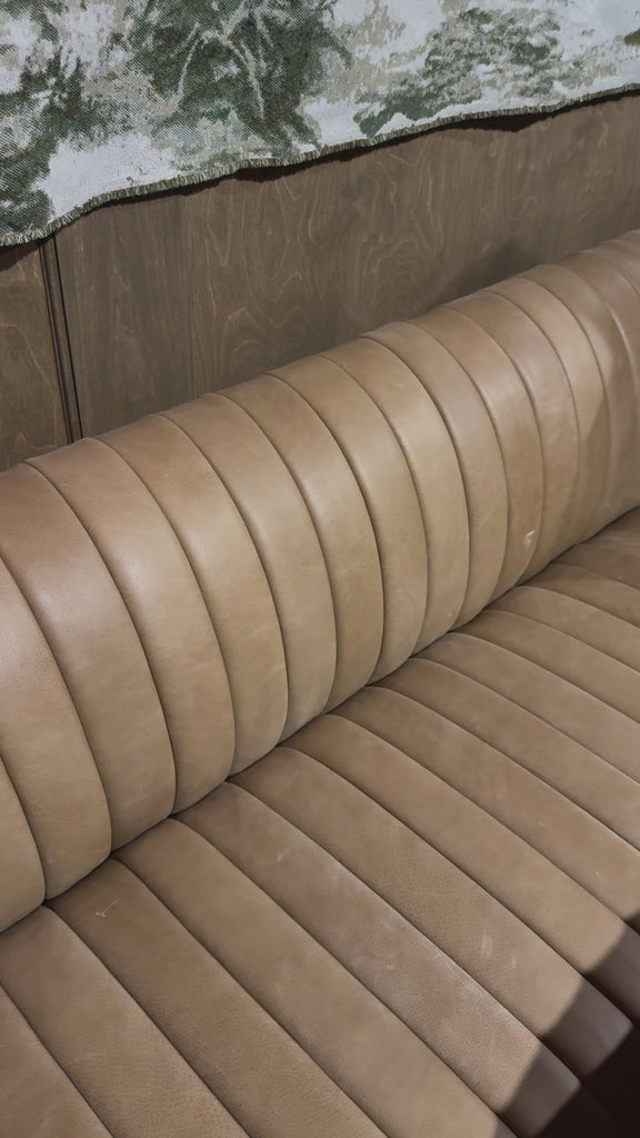 Welcome to your new favorite nook for morning coffee. An L-shaped dining banquette is upholstered in tan top-grain leather with a beautifully pronounced grain and dramatic channeling for a linear look.Overall Dimensions: 110.00"w x 66.50"d x 31.50"h Amethyst Home provides interior design, new home construction design consulting, vintage area rugs, and lighting in the Newport Beach metro area.