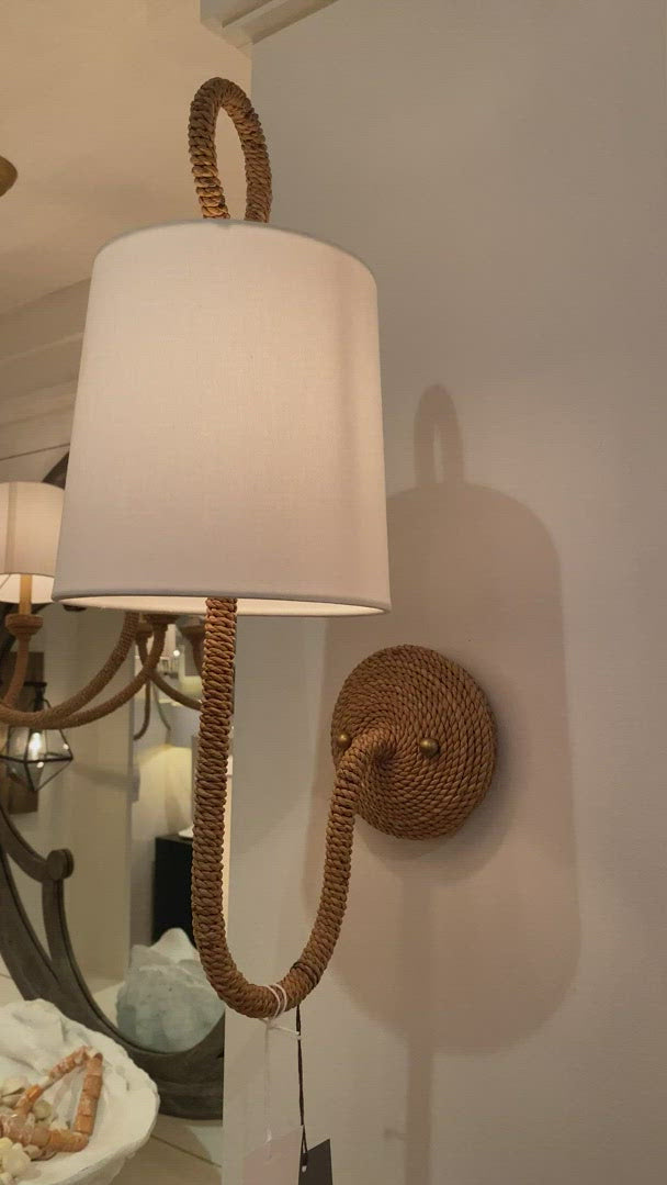 Natural woven rattan provides a "washed ashore" look on the Bimini sconce. Looped detailing also provides a nautical touch, while natural linen shades tailor the look. Install these in a hallway of a coastal or rustic home to tie its design together.    Overall size: 20.5"h x 7"w x 11"d