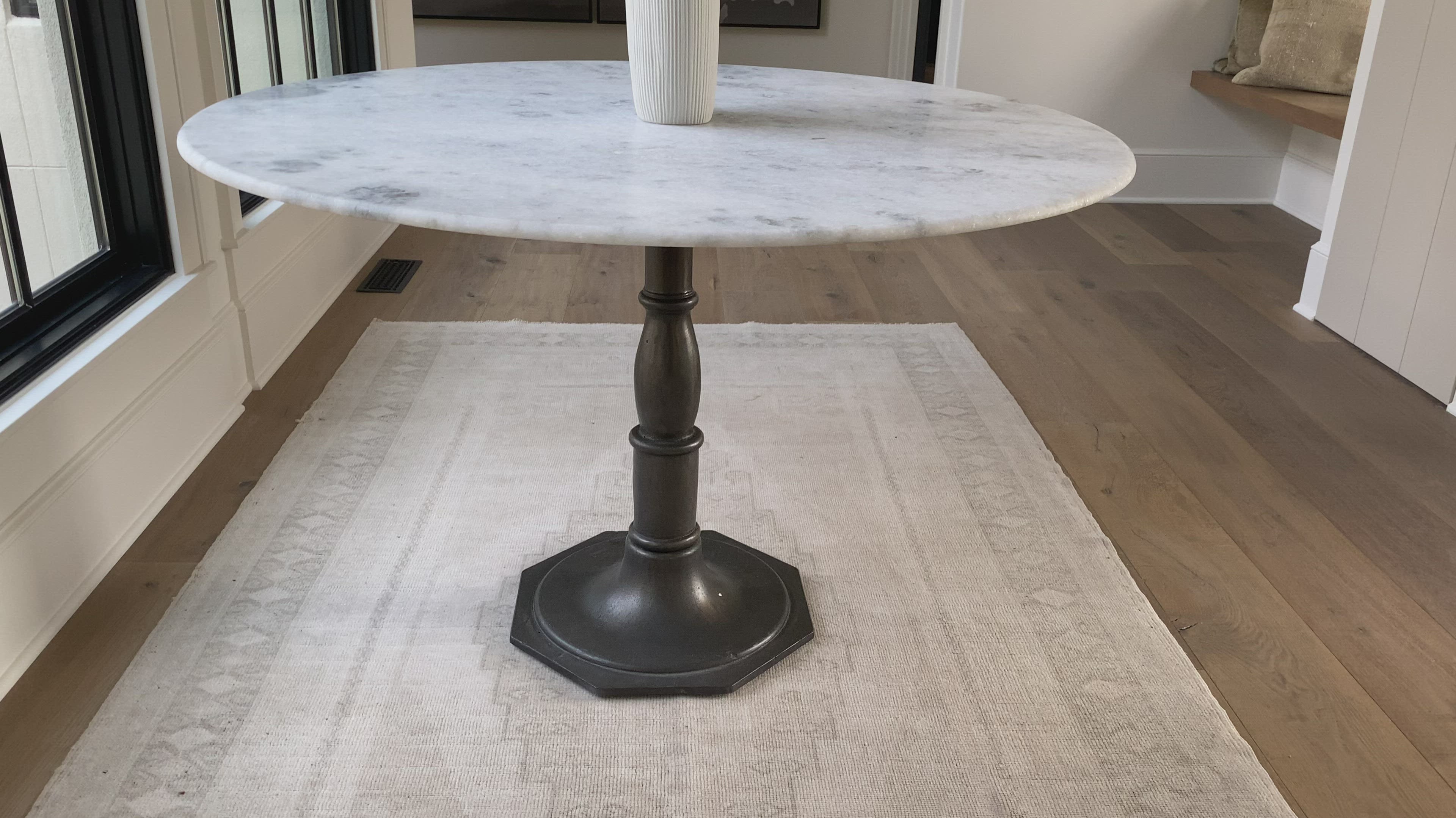 French-industrial meets bistro table. Detailed, 8-sided cast iron pedestal supports a dramatic white marble top with bull-nosed edge.  Overall Size: 36.00"w x 36.00"d x 31.00"h  Colors: Carbon Wash, White Marble Materials: Iron, Marble