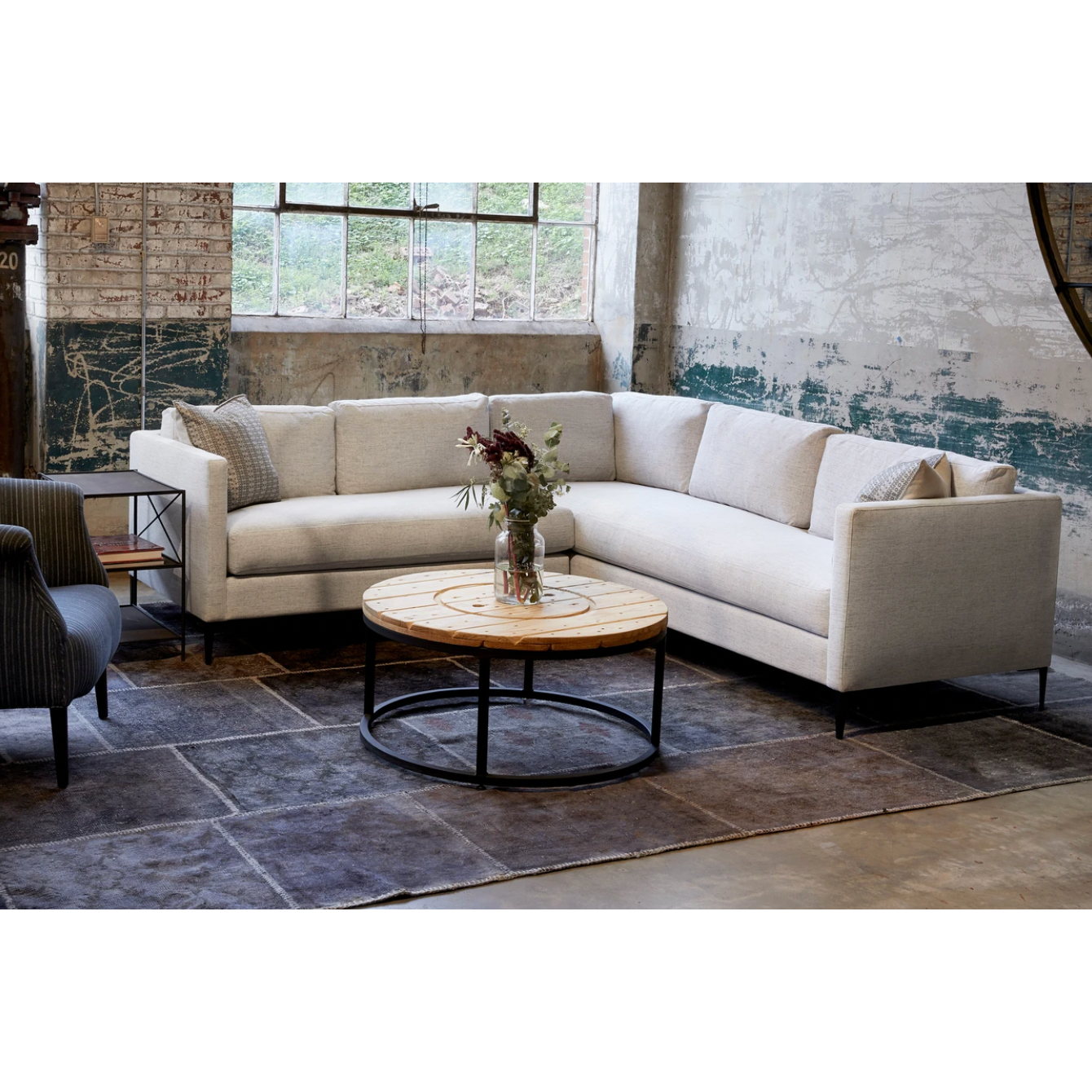 The Benedict 2 Arm Sectional - Essentials by Cisco Brothers is a modern design with clean lines and sleek metal legs in black rust. It has a fresh and functional aesthetic with no-sag support. Photographed in Vanocur Natural and Navedo Gravel.  Overall: 96"w x 96"d x 29"h