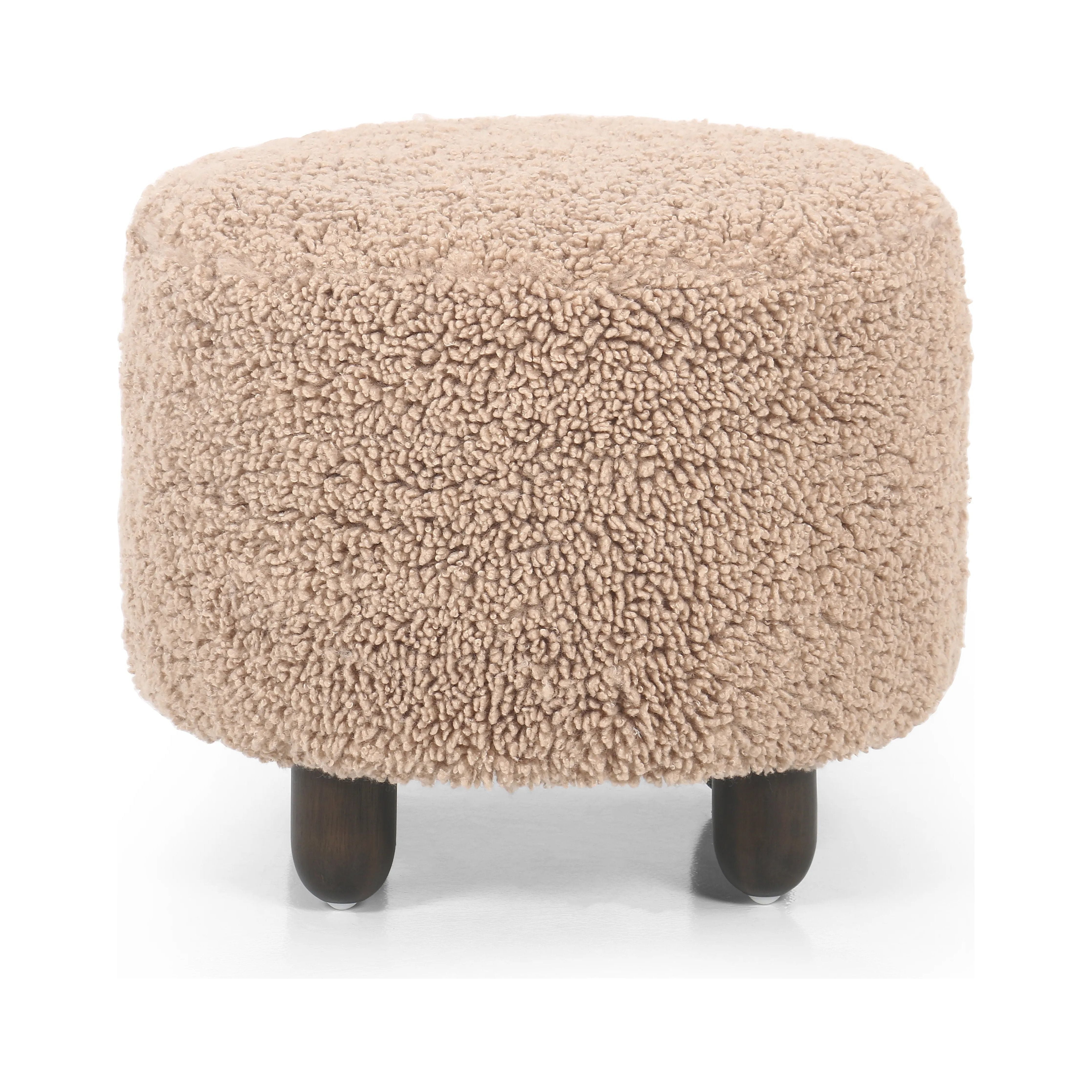 Place this round ottoman just about anywhere. Upholstered in a faux Mongolian shearling with a high pile fur in a toasty tan neutral hue. Burnt birch parawood legs add a touch of contrast.Collection: Kensingto Amethyst Home provides interior design, new home construction design consulting, vintage area rugs, and lighting in the Boston metro area.