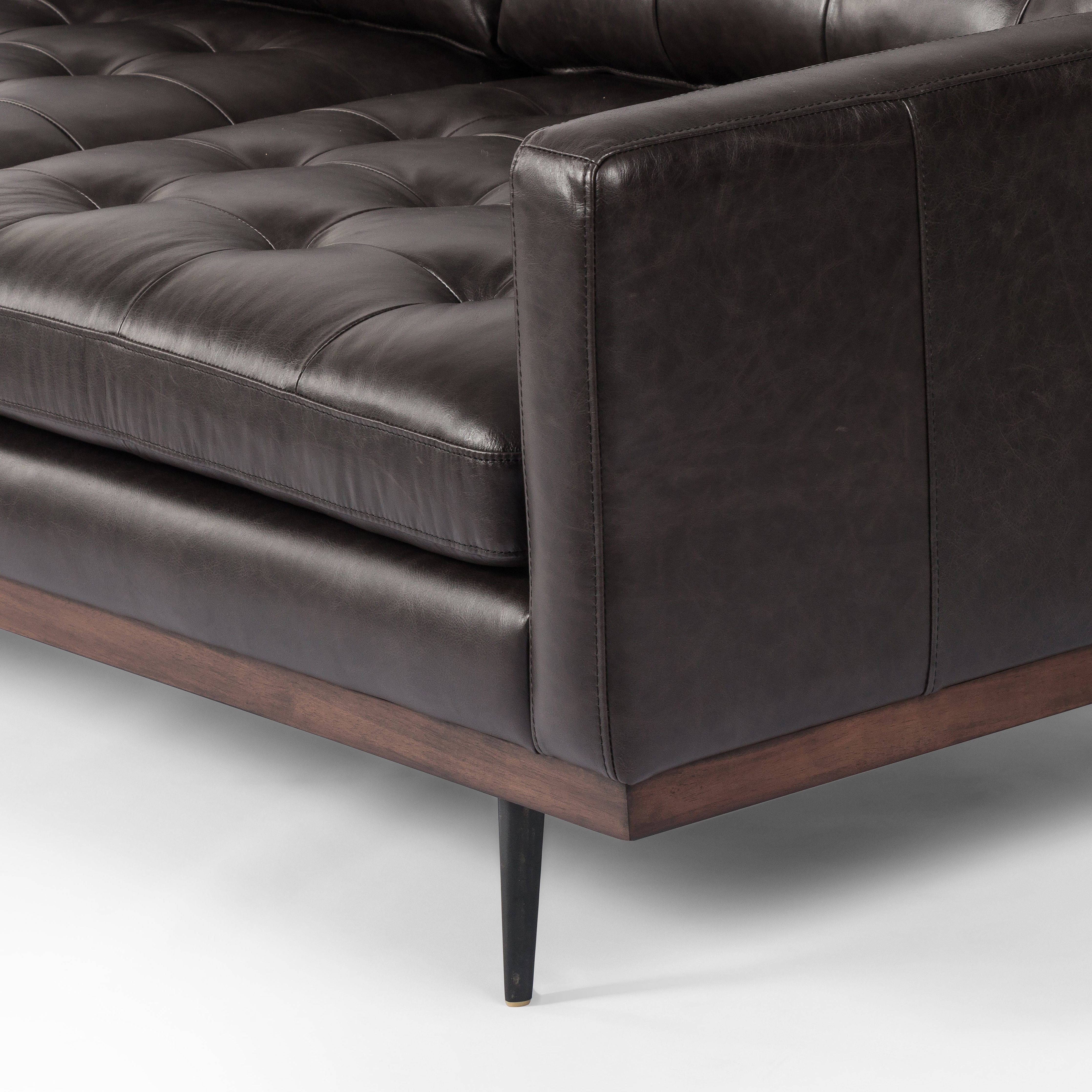 Low-leaning style with mid-century vibes. Upholstered in an exclusive subtly distressed black top-grain leather, with button tufting for texture and comfort. Finished with wrap-around framing and cone-tapered legs. Amethyst Home provides interior design, new construction, custom furniture, and area rugs in the Salt Lake City metro area.