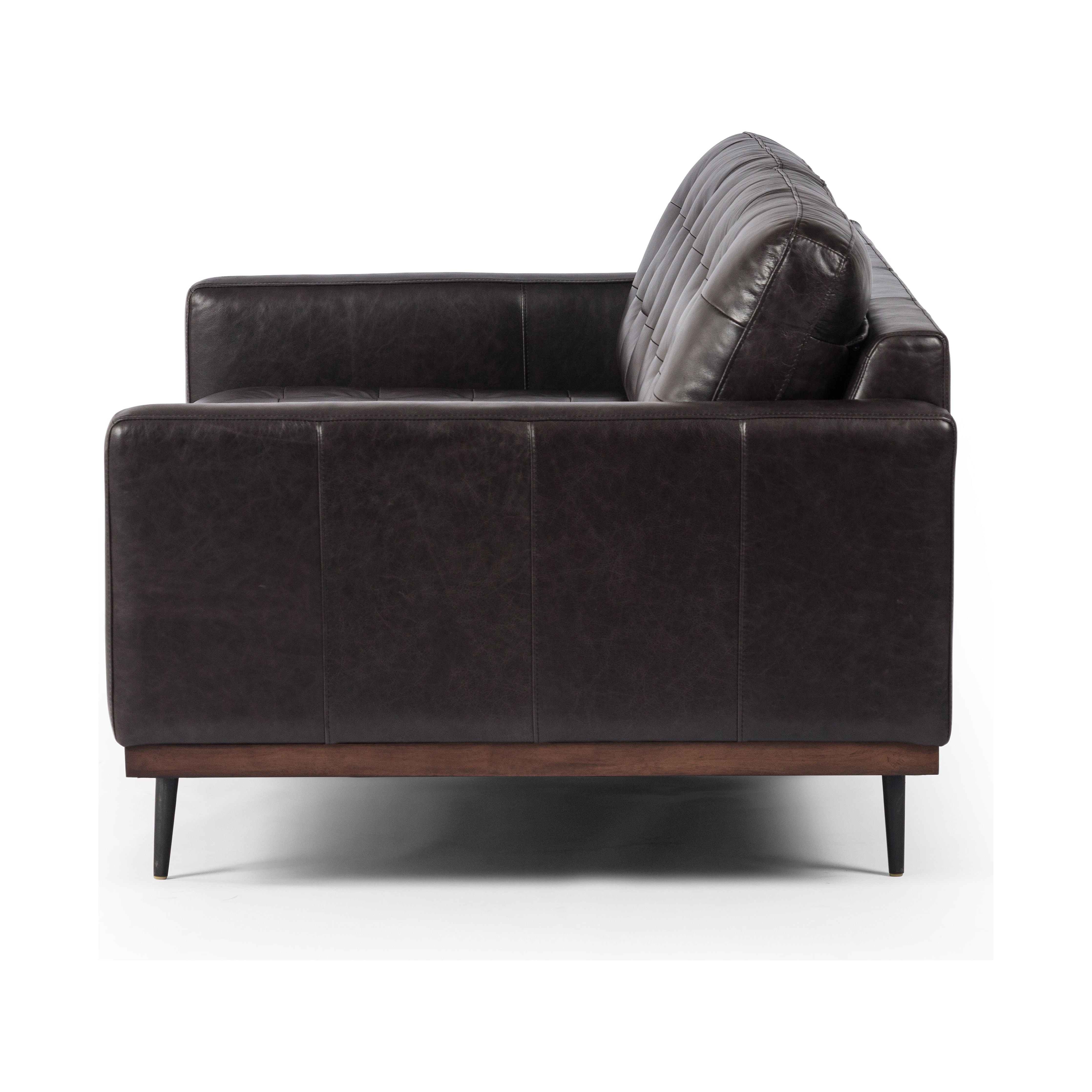 Low-leaning style with mid-century vibes. Upholstered in an exclusive subtly distressed black top-grain leather, with button tufting for texture and comfort. Finished with wrap-around framing and cone-tapered legs. Amethyst Home provides interior design, new construction, custom furniture, and area rugs in the Seattle metro area.
