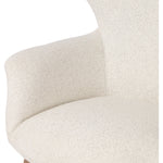The classic wingback chair is updated with a midcentury-style base. Flared arms and a high winged back with blind tufting offer all-around comfort. Upholstered in a heavily textured boucle performance fabric bringing movement and everyday function to the piece. Amethyst Home provides interior design, new construction, custom furniture, and area rugs in the Houston metro area.