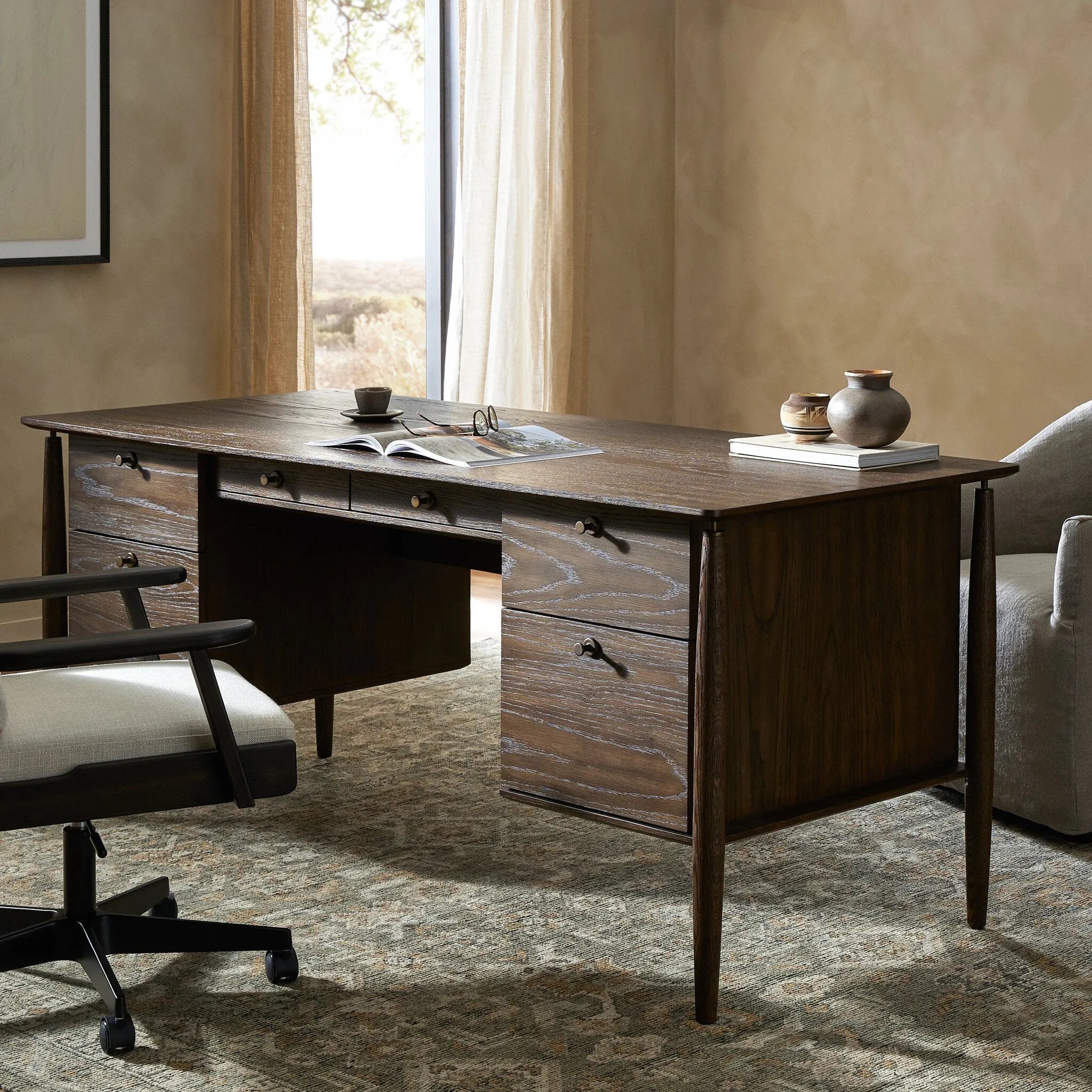 An executive-style desk of aged oak, inspired by European antiques. Turned, cylindrical legs adapt this charming heirloom-inspired piece for the modern home office and beyond.Collection: Haide Amethyst Home provides interior design, new home construction design consulting, vintage area rugs, and lighting in the Monterey metro area.