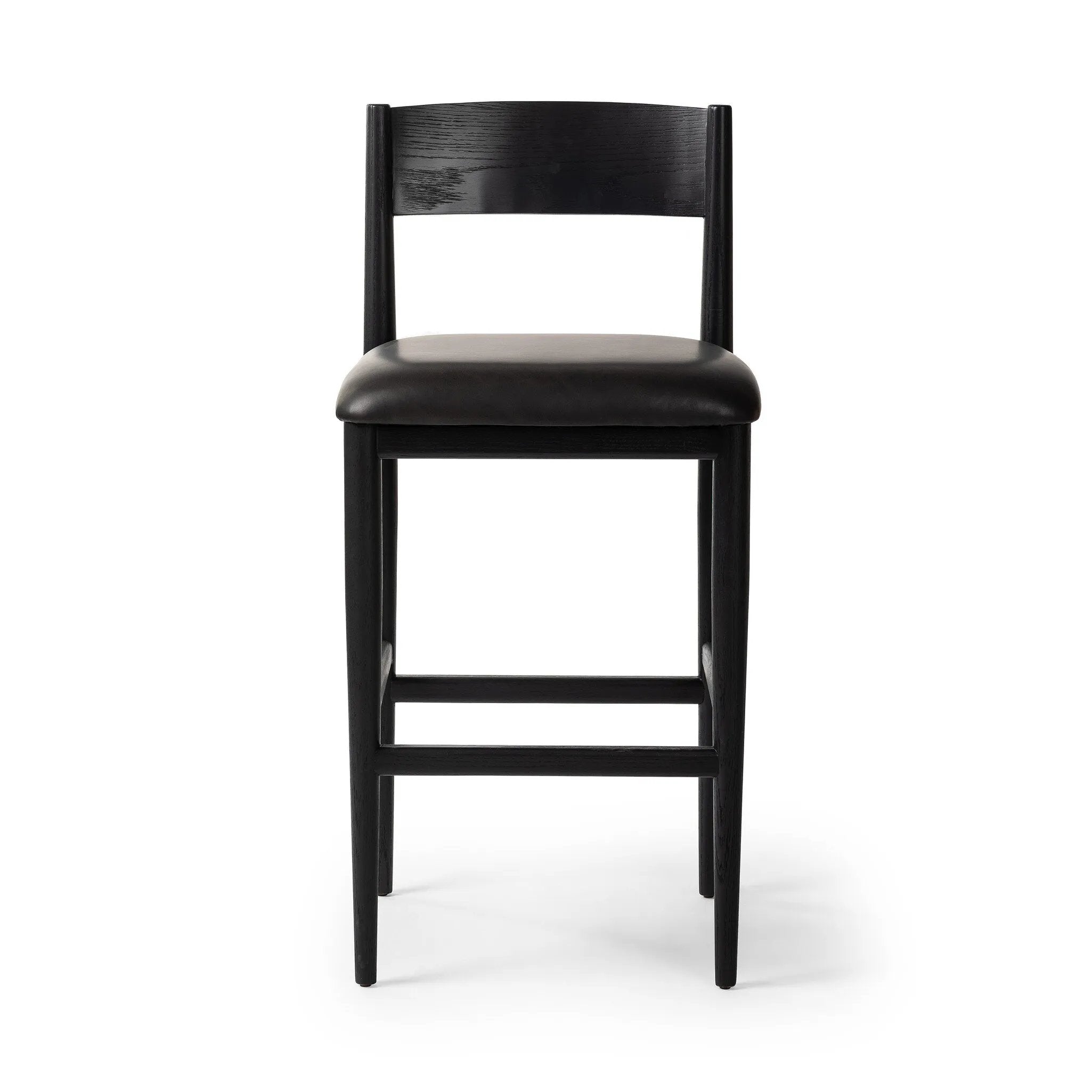 Monochromatic meets midcentury with this bar-height stool. Structured while comfortable, the tapered-leg chair pairs an ebony wood frame with a faux leather cushion.Collection: Ashfor Amethyst Home provides interior design, new home construction design consulting, vintage area rugs, and lighting in the Dallas metro area.