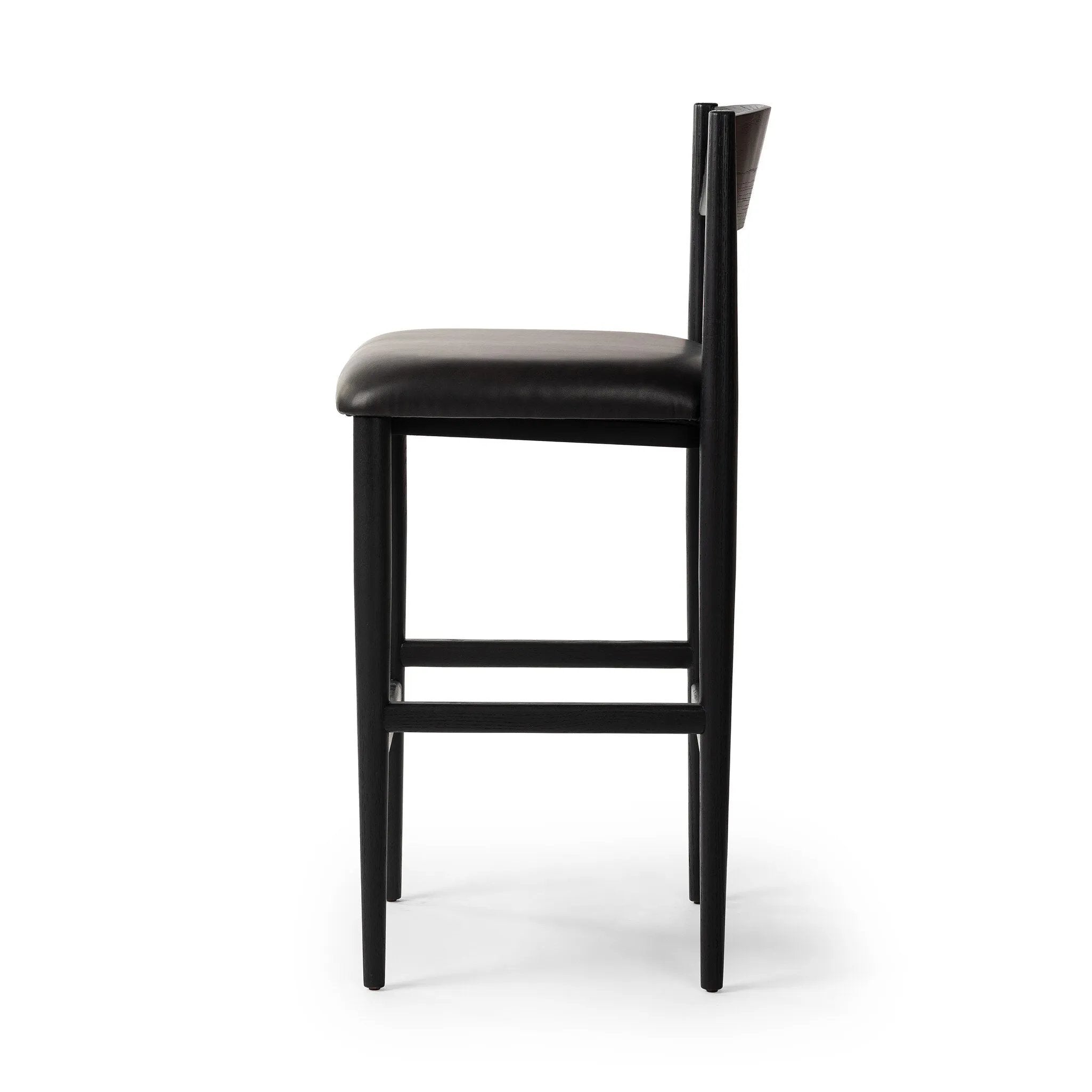 Monochromatic meets midcentury with this bar-height stool. Structured while comfortable, the tapered-leg chair pairs an ebony wood frame with a faux leather cushion.Collection: Ashfor Amethyst Home provides interior design, new home construction design consulting, vintage area rugs, and lighting in the Miami metro area.