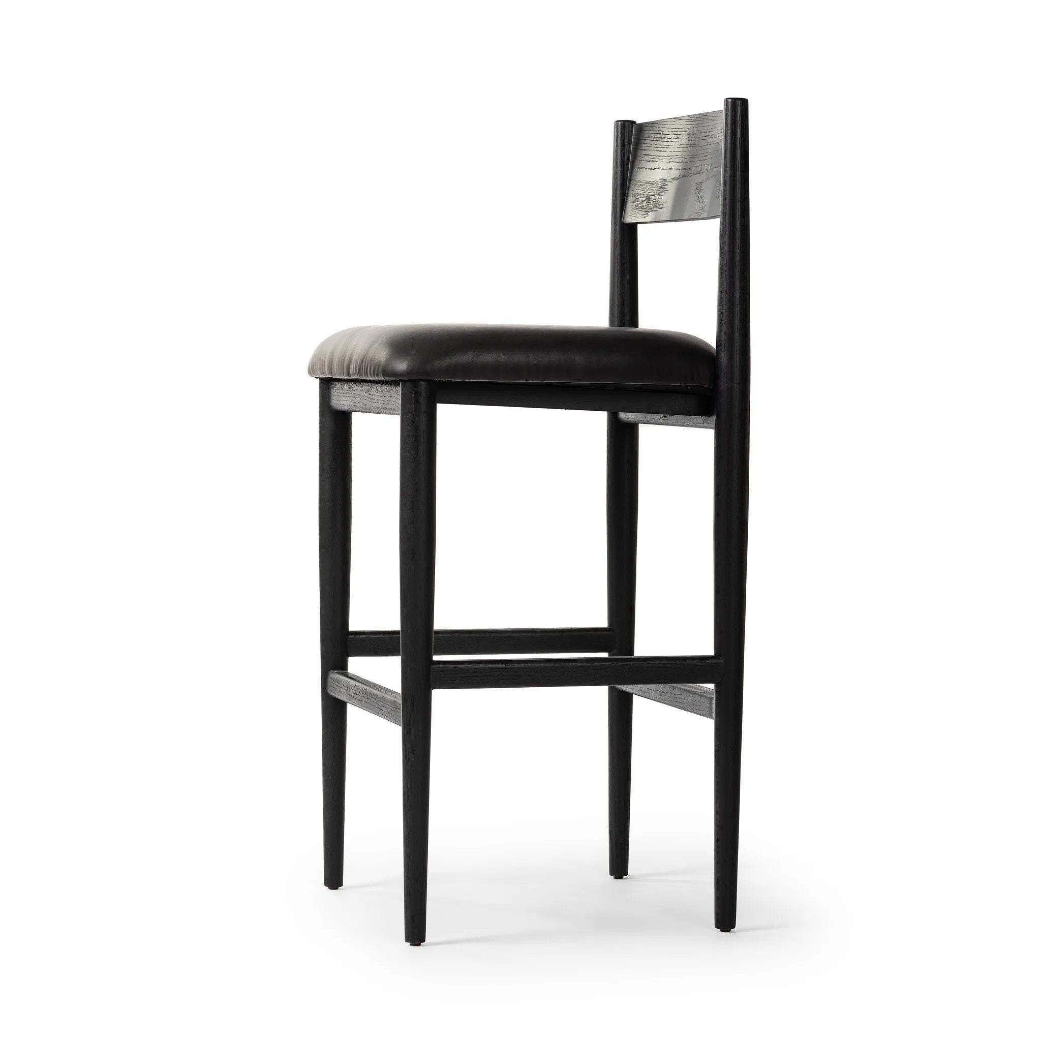 Monochromatic meets midcentury with this bar-height stool. Structured while comfortable, the tapered-leg chair pairs an ebony wood frame with a faux leather cushion.Collection: Ashfor Amethyst Home provides interior design, new home construction design consulting, vintage area rugs, and lighting in the Nashville metro area.