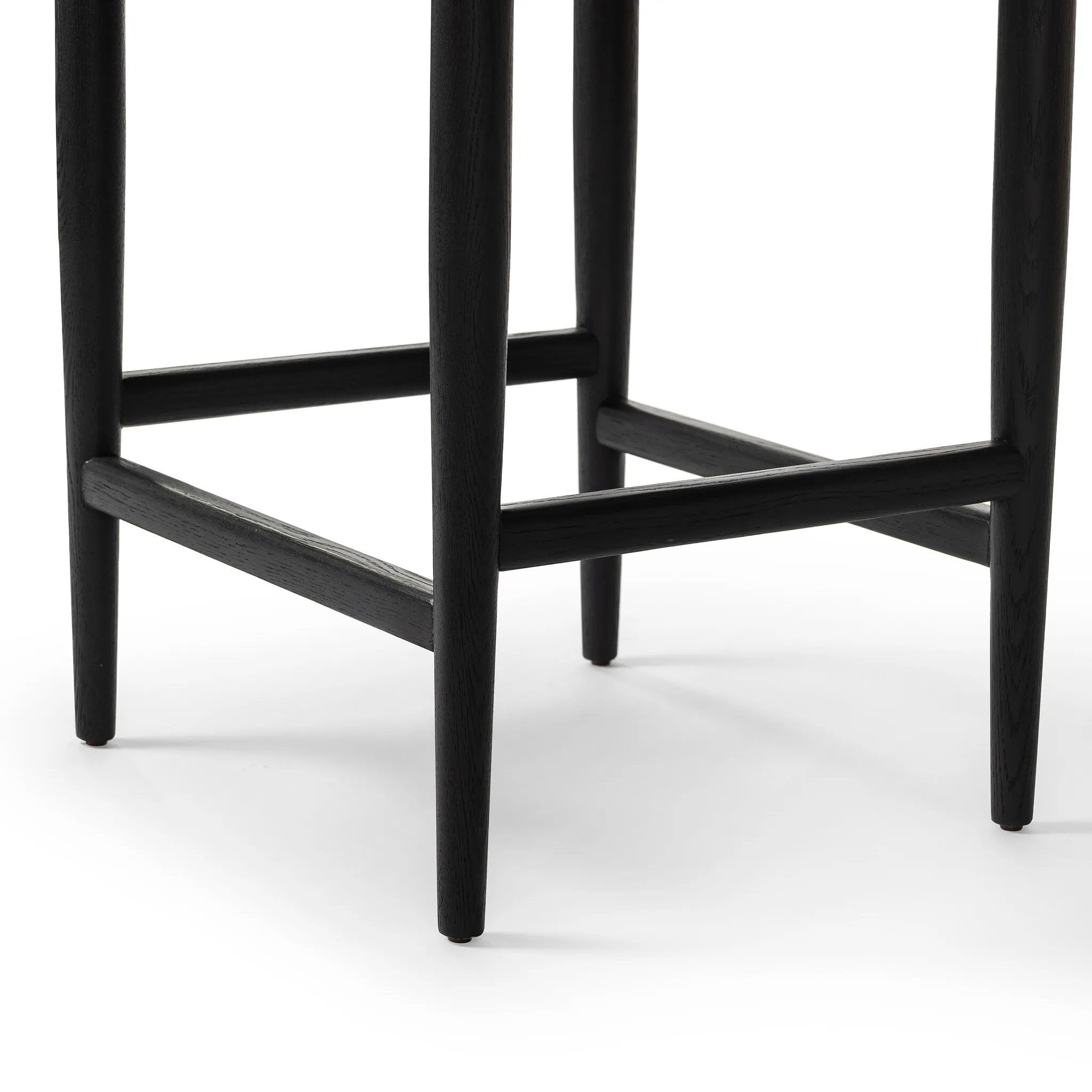 Monochromatic meets midcentury with this counter-height stool. Structured while comfortable, the tapered-leg chair pairs an ebony wood frame with a faux leather cushion.Collection: Ashfor Amethyst Home provides interior design, new home construction design consulting, vintage area rugs, and lighting in the Tampa metro area.