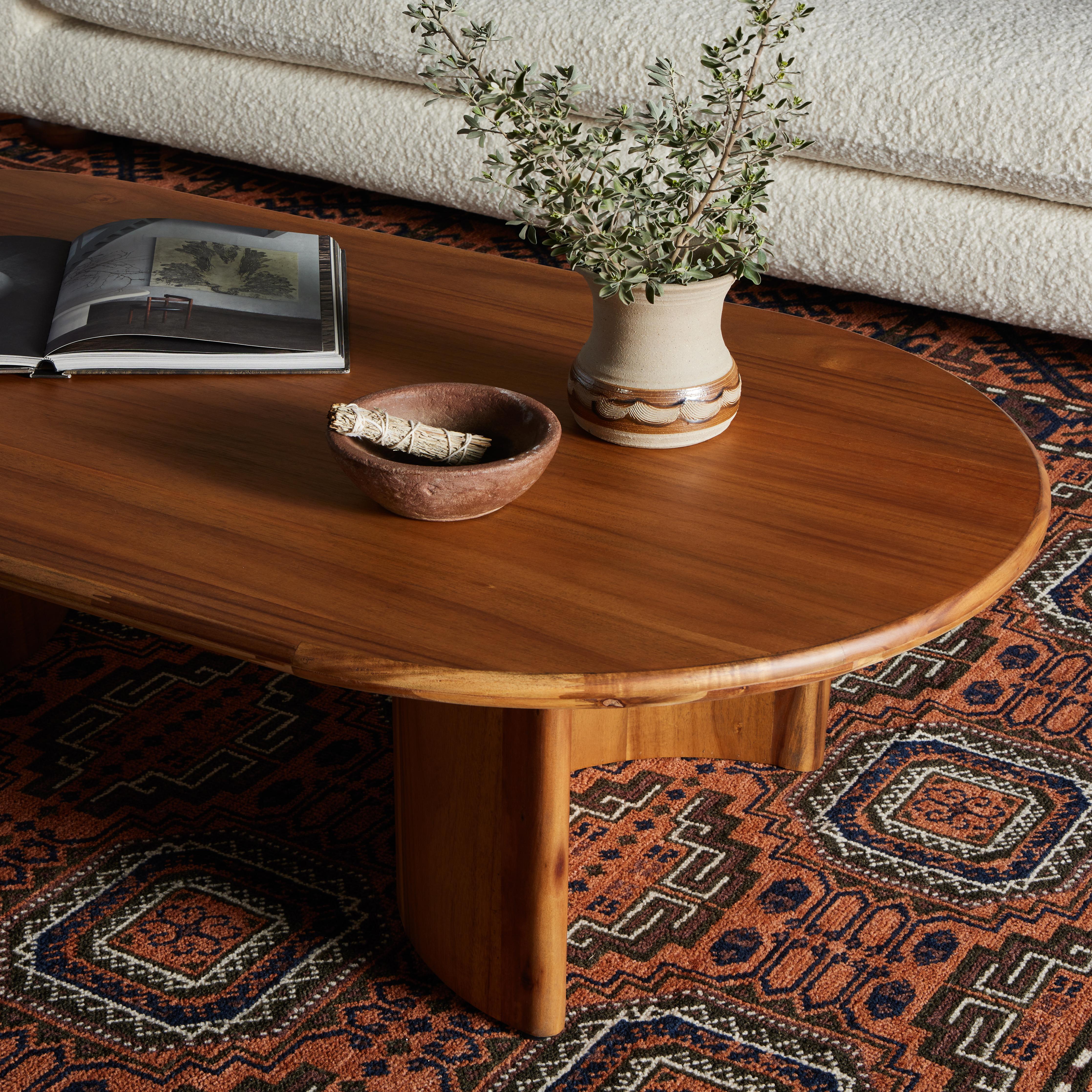 A study in shape. Solid brown acacia forms crescent-shaped legs and sprawling oval tabletop, bringing organic presence to the living room. Amethyst Home provides interior design, new home construction design consulting, vintage area rugs, and lighting in the Des Moines metro area.