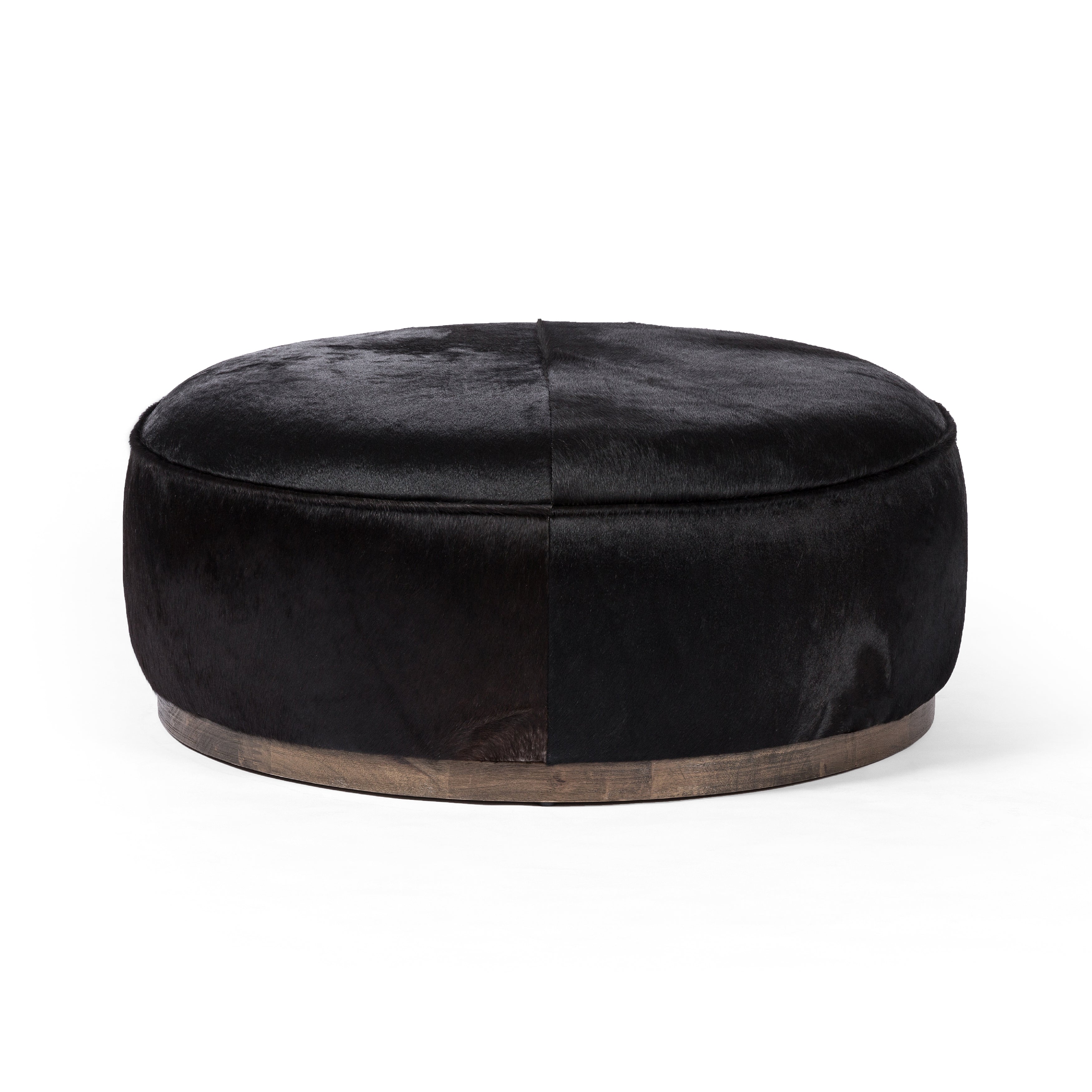 This large, round ottoman of textural hair-on hide brings with it a hip retro vibe as a coffee table or extra seating.  Covered in soft and luminous black hair-on hide, which is naturally warm and textural with authentic highlights. Amethyst Home provides interior design, new construction, custom furniture, and area rugs in the Newport Beach metro area.