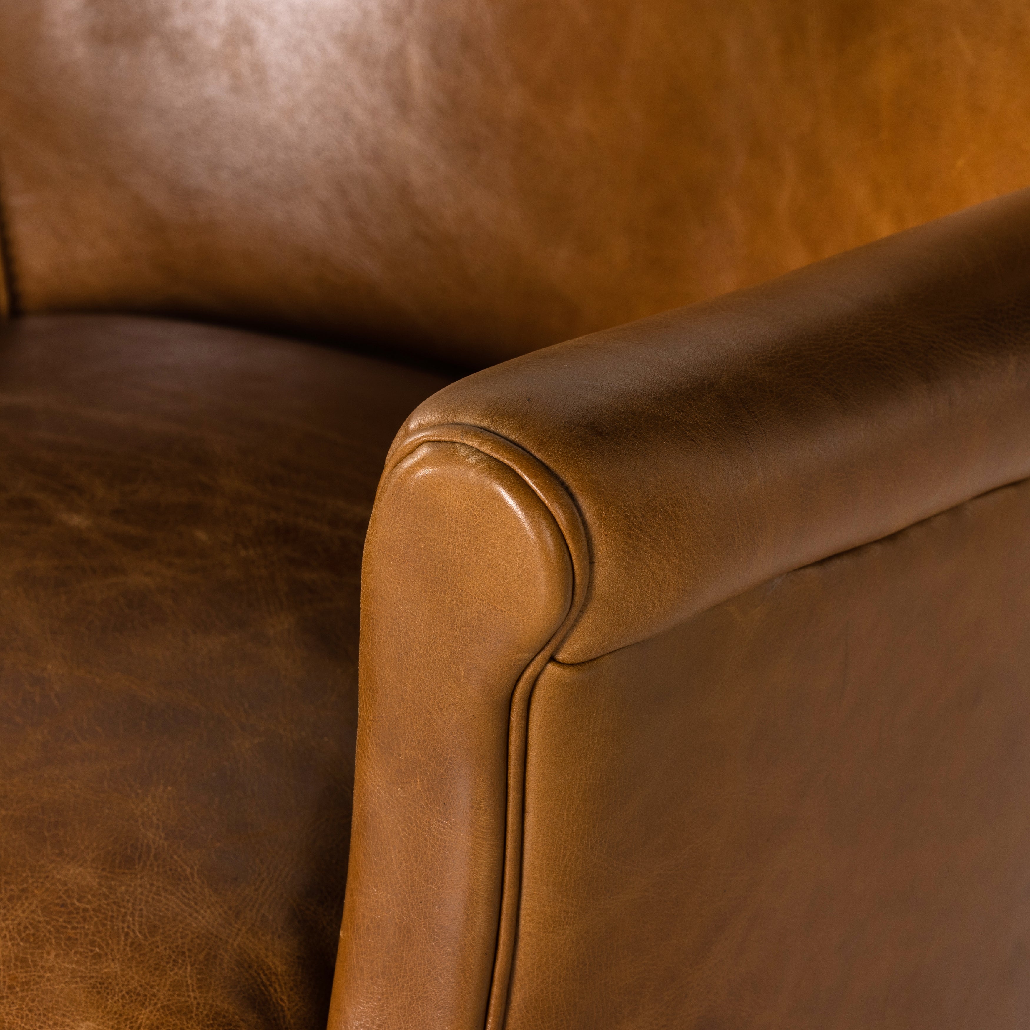 A statement seat all its own. This regal Parisian club chair is honored with a profound scooped back and rolled arms in classic, lived in tan top-grain leather. Amethyst Home provides interior design, new construction, custom furniture, and area rugs in the Des Moines metro area.
