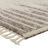 Inspired by textiles from the Tullu region in Morocco, the Patra area rug showcases a linear design in neutral shades of cream, taupe, brown, and gray. This high-piled accent lends warmth and comfort to any space with durable wool hand-knotted onto a cotton foundation. Braided fringe trims the edges for a touch of boho charm. Amethyst Home provides interior design, new home construction design consulting, vintage area rugs, and lighting in the Houston metro area.