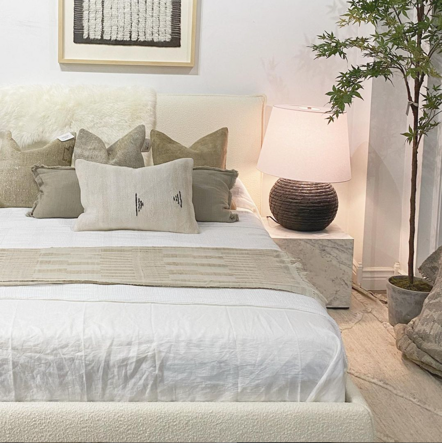 White cream boucle bed at Amethyst Home with Nash marble side table and Iman rug by Loloi.