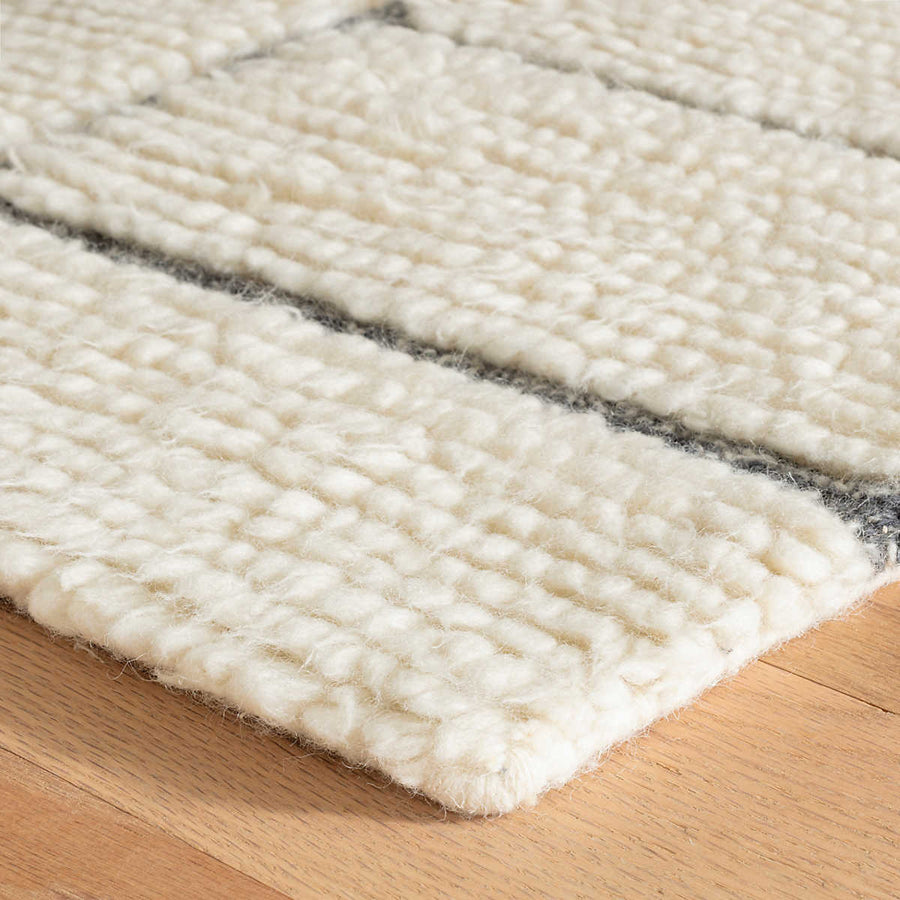 Wooly and soft, the enviable texture of this densely shaggy wool rug is a unique statement of pure, natural beauty. High pile tufts are hand-worked into blocks filled with corded furrows to create a rich, cozy, and layered landscape. Bold intersecting lines of woven nubby, marled Charcoal bring contrast and graphic structure to the Ivory softness. Amethyst Home provides interior design services, furniture, rugs, and lighting in the Kansas City metro area.