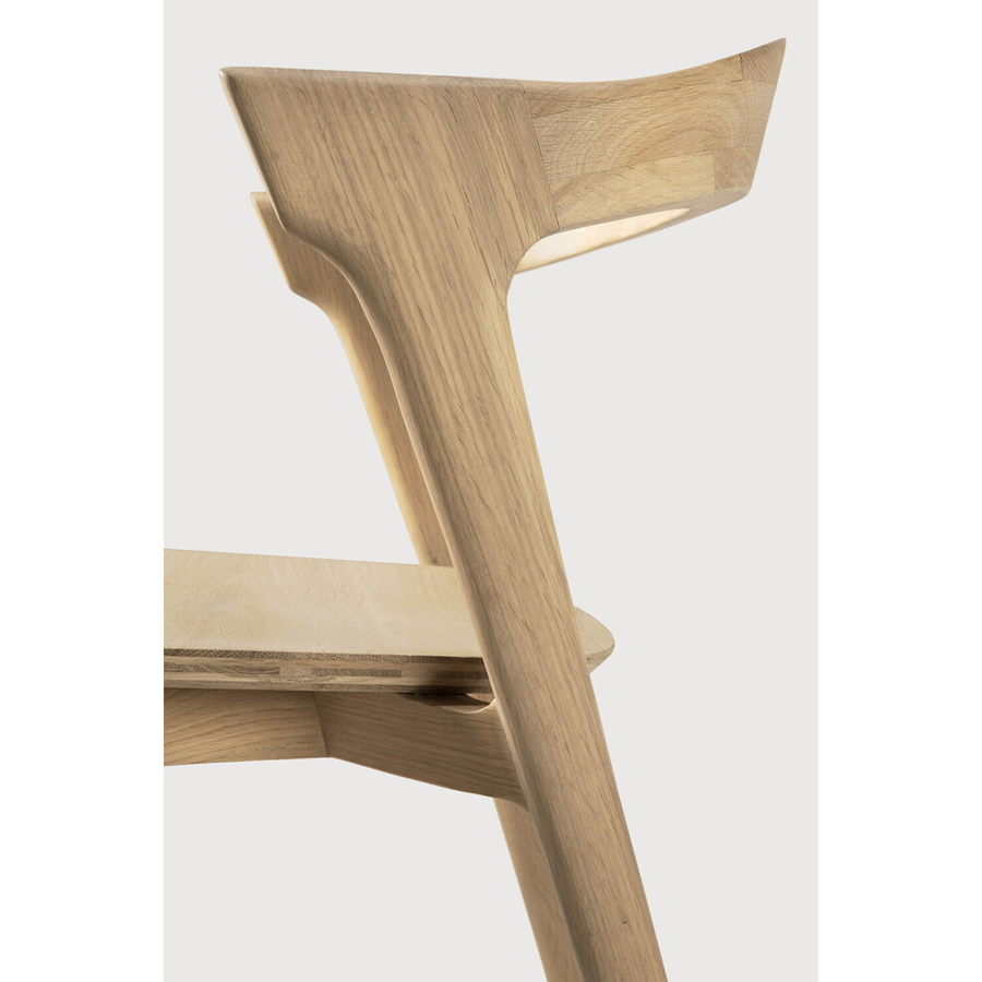 This Oak Bok Dining Chair features an airy shape with rock-solid construction,  making this piece a timeless and remarkable design to enjoy for years to come. Pair with a dining table or stand-alone against a wall, hallway, or end of the bed! Designed by Alain can Havre  Dimensions: 20"w x 21.5"d x 30"h  Weight: 20 lbs  Seat Height: 18"  Material: Oak, 100% solid wood Finish: Oiled