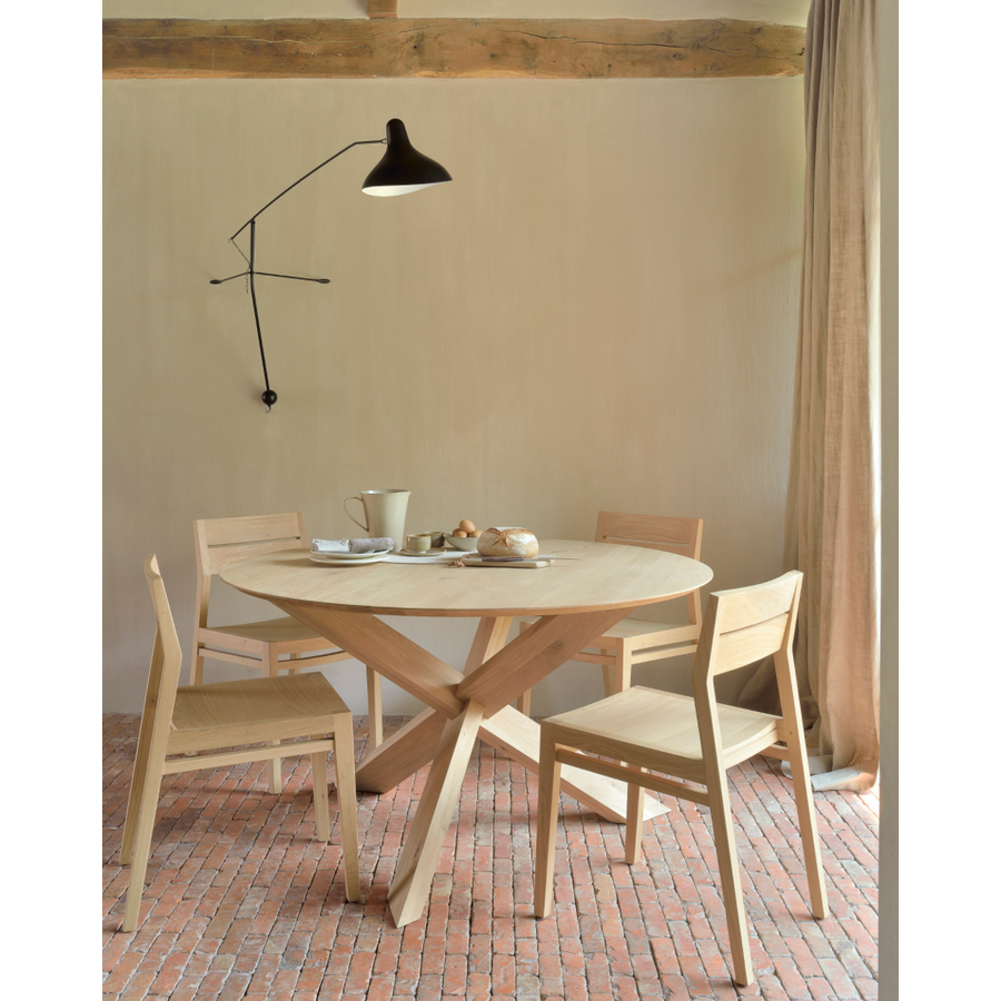 This Oak Circle Round Dining Table is all about inspiring your family to spend a little more time at the table. The solid legs intertwine in perfect balance to create a unique, bright look to any kitchen or dining area.   Material: Oak, 100% Solid Wood Finish: Varnished