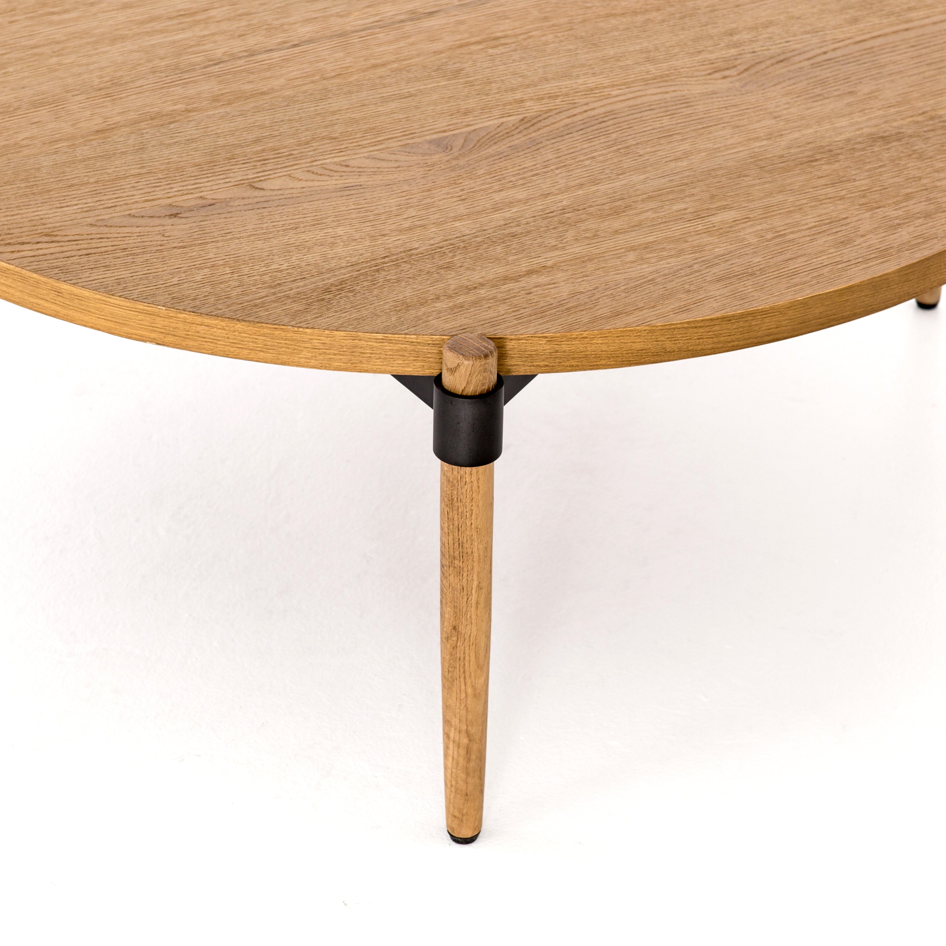 Stunning simplicity with a Danish-inspired spin. A rounded tabletop of smoked drift oak offsets a triad of slim, tapered legs. Waxed black joinery adds a fresh look of high contrast. Pair with matching cocktail table for a nested, layered look.  Overall Dimensions: 43"w x 43"d x 14.75"h   Colors: Waxed Black, Smoked Drift Oak Materials: Iron, Oak