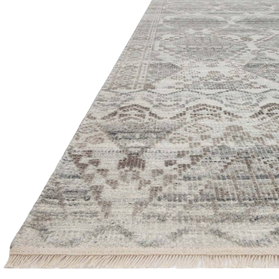 The Idris Stone area rug from Loloi is meticulously hand-knotted of viscose and wool. You will love this rug because the rug is:  Perfect for entryways, living rooms, and bedrooms Easy to clean and maintain Gorgeous with the intricate pattern and patina Warms up any room with the high / low pile Hand-Knotted 70% Viscose | 30% Wool ID-01 Stone