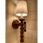 This Perennial Sconce - Natural is hand lathed from solid wood and distressed for a rustic chic effect. The added faux drip wax details on the candle sleeves add to the charm and relaxed coastal style to any living room, bedroom, or other space.   Overall Dimensions: 6"w x 7"d x 19"h